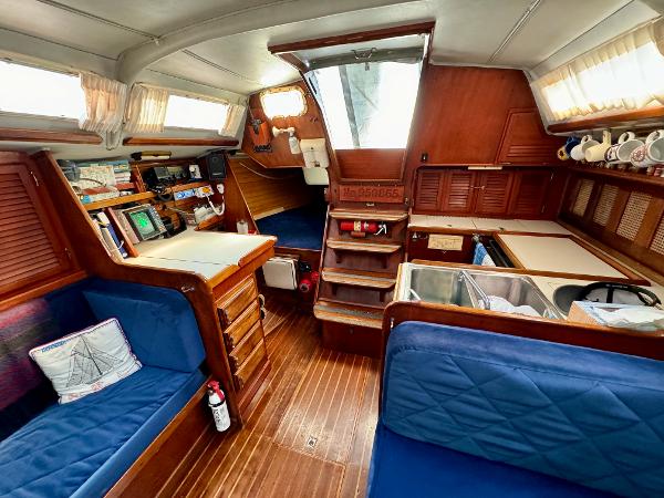 Interior of 1979 Islander IP Peterson 40 sailboat with wood finish and blue seating.