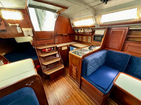 Interior of 1979 Islander IP Peterson 40 sailboat with wooden finish and blue seating.