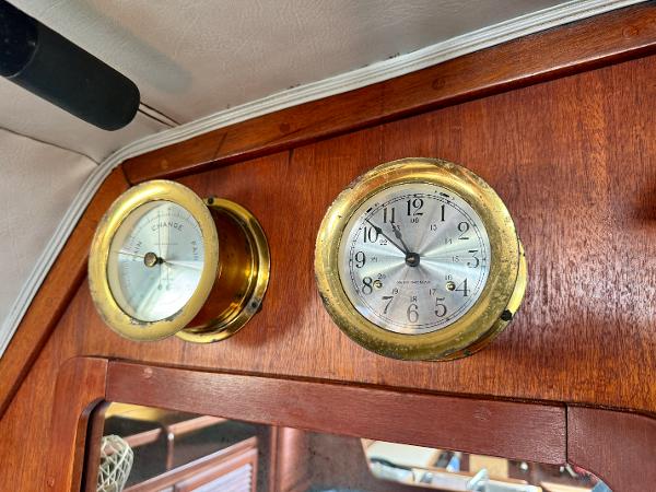 Brass clock and barometer on 1979 Islander IP Peterson 40 yacht's wooden interior.