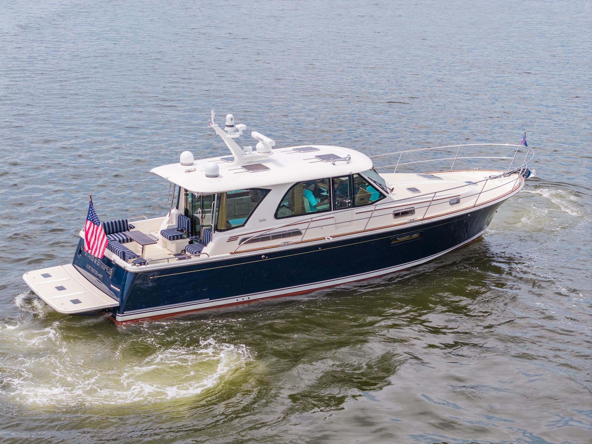 2024 Sabre 43 Salon Express yacht cruising on open water, displaying American flag.