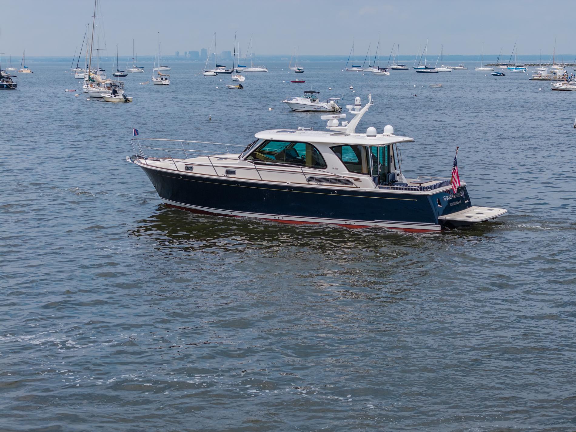 2024 Sabre 43 Salon Express yacht cruising in a busy harbor with sailboats.