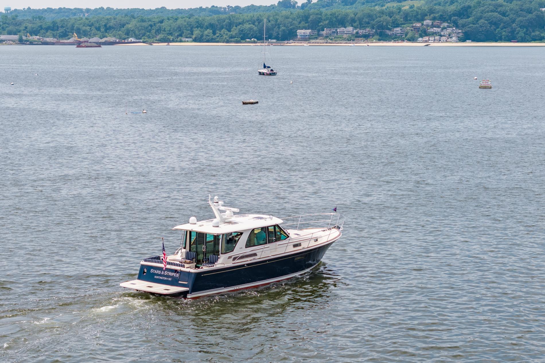 2024 Sabre 43 Salon Express cruising on a scenic lake with distant shoreline.