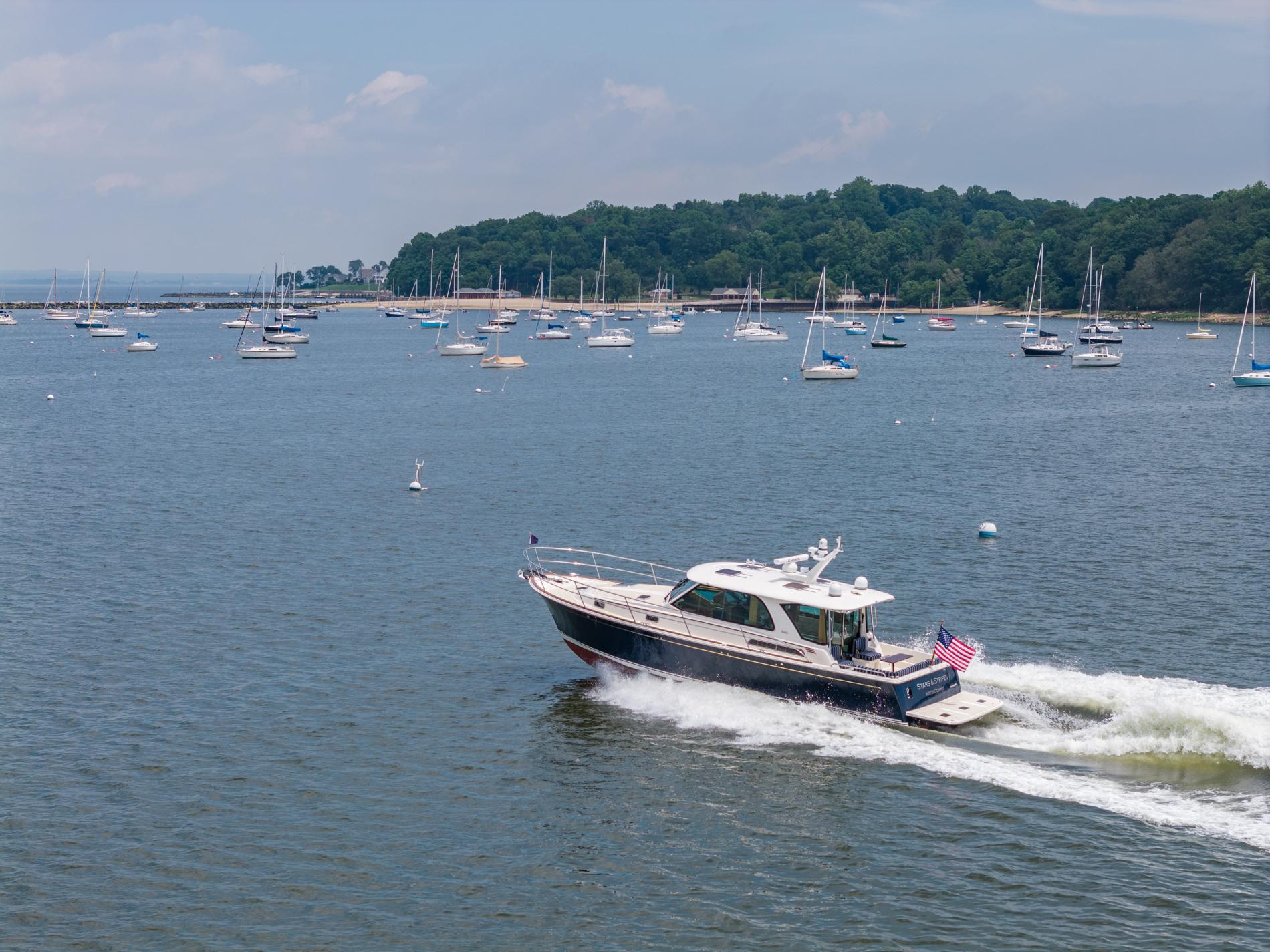 2024 Sabre 43 Salon Express cruising in a scenic bay with numerous anchored sailboats.