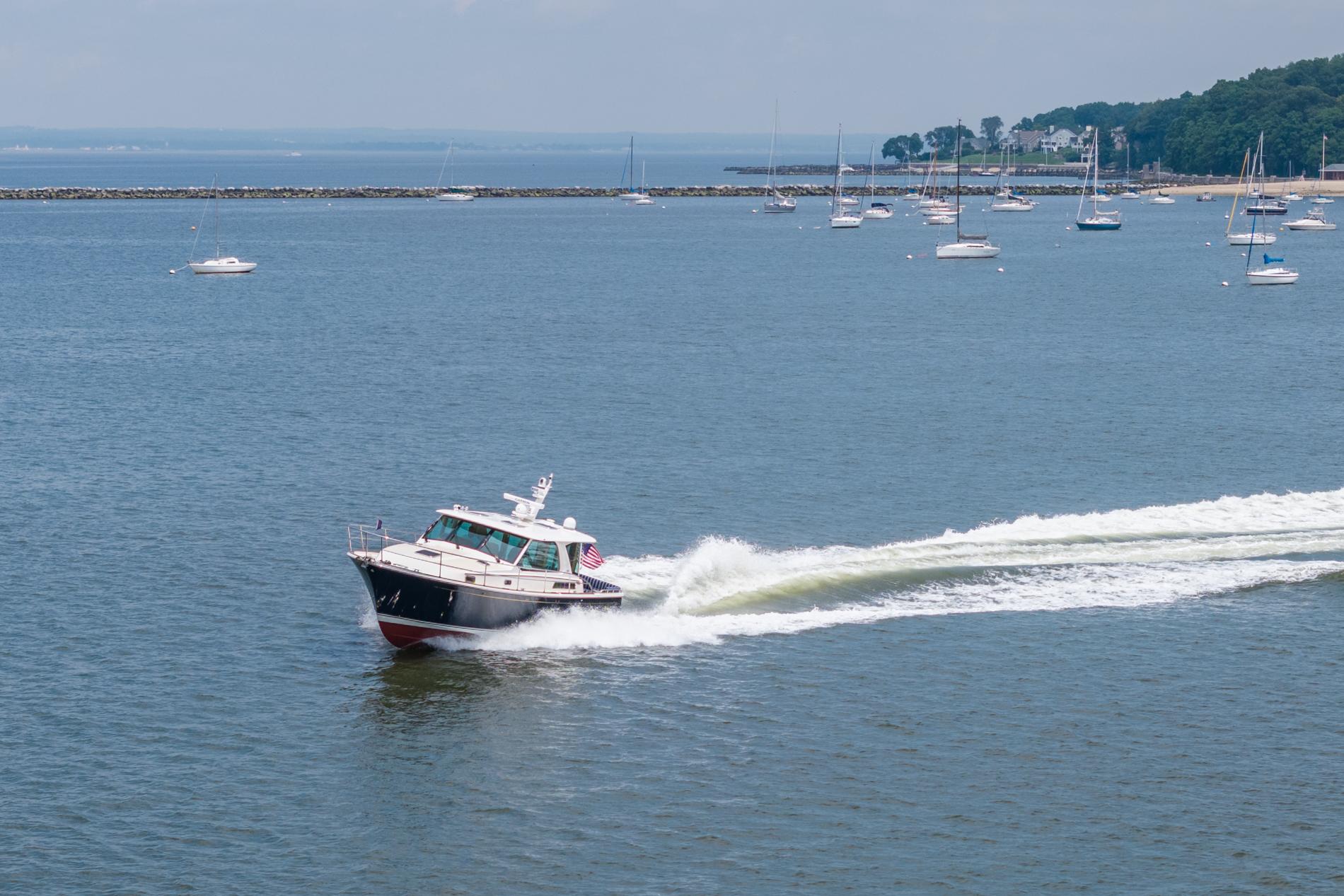2024 Sabre 43 Salon Express cruising on a scenic bay with sailboats in the background.