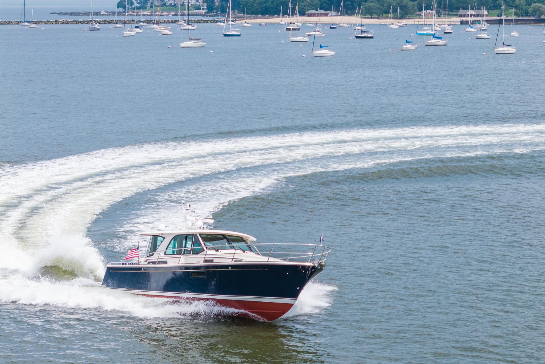 2024 Sabre 43 Salon Express cruising on a scenic bay with sailboats in the background.