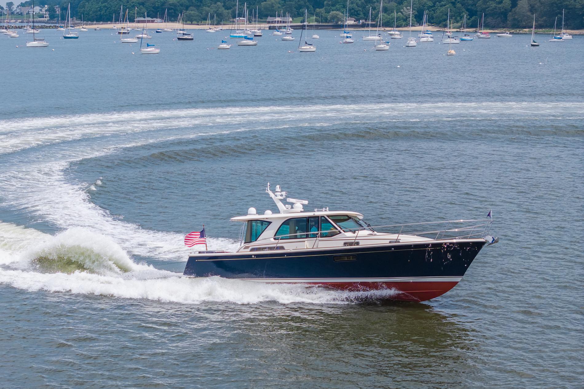2024 Sabre 43 Salon Express yacht cruising on a scenic lake with sailboats.