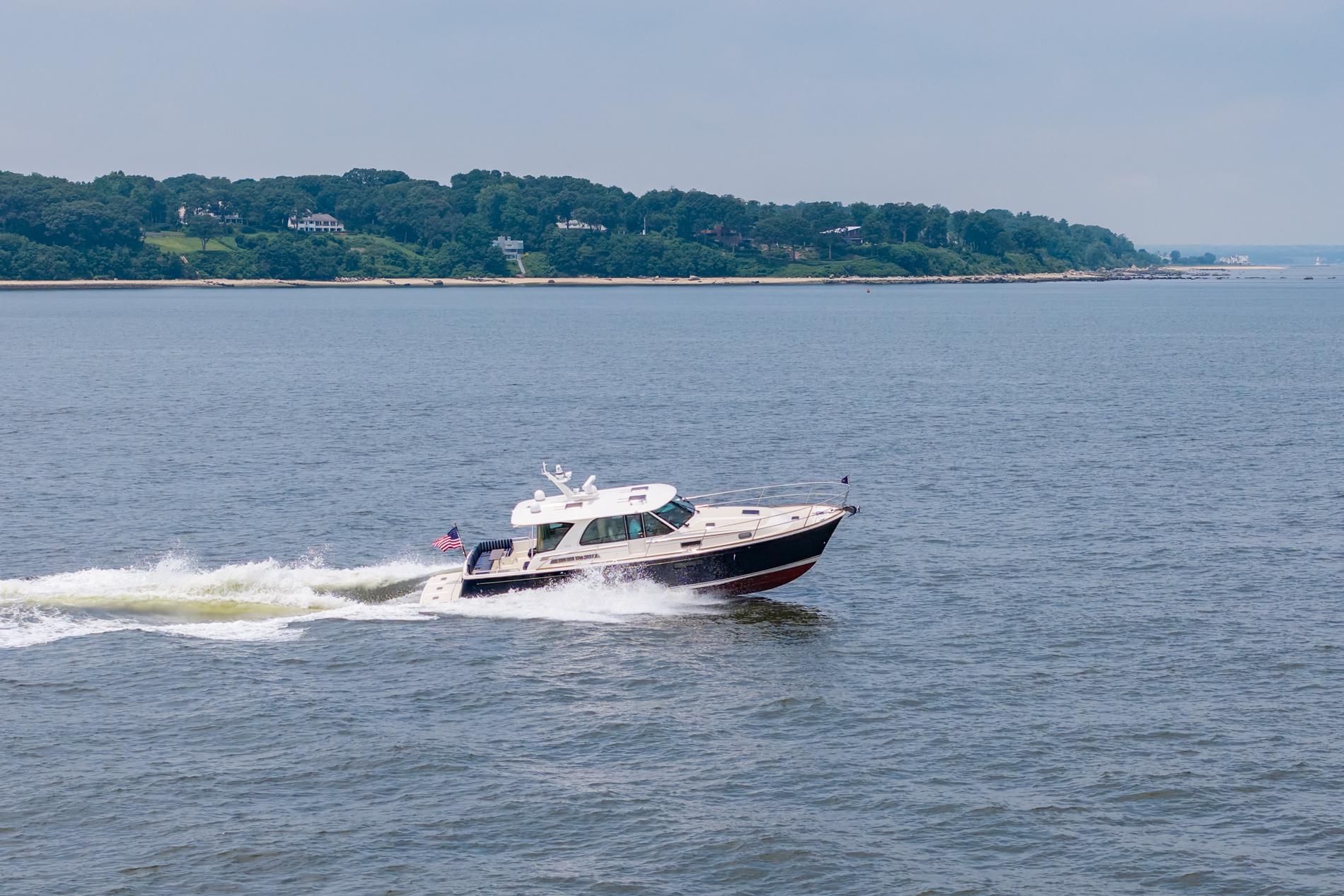 2024 Sabre 43 Salon Express cruising on open water near a lush coastline.