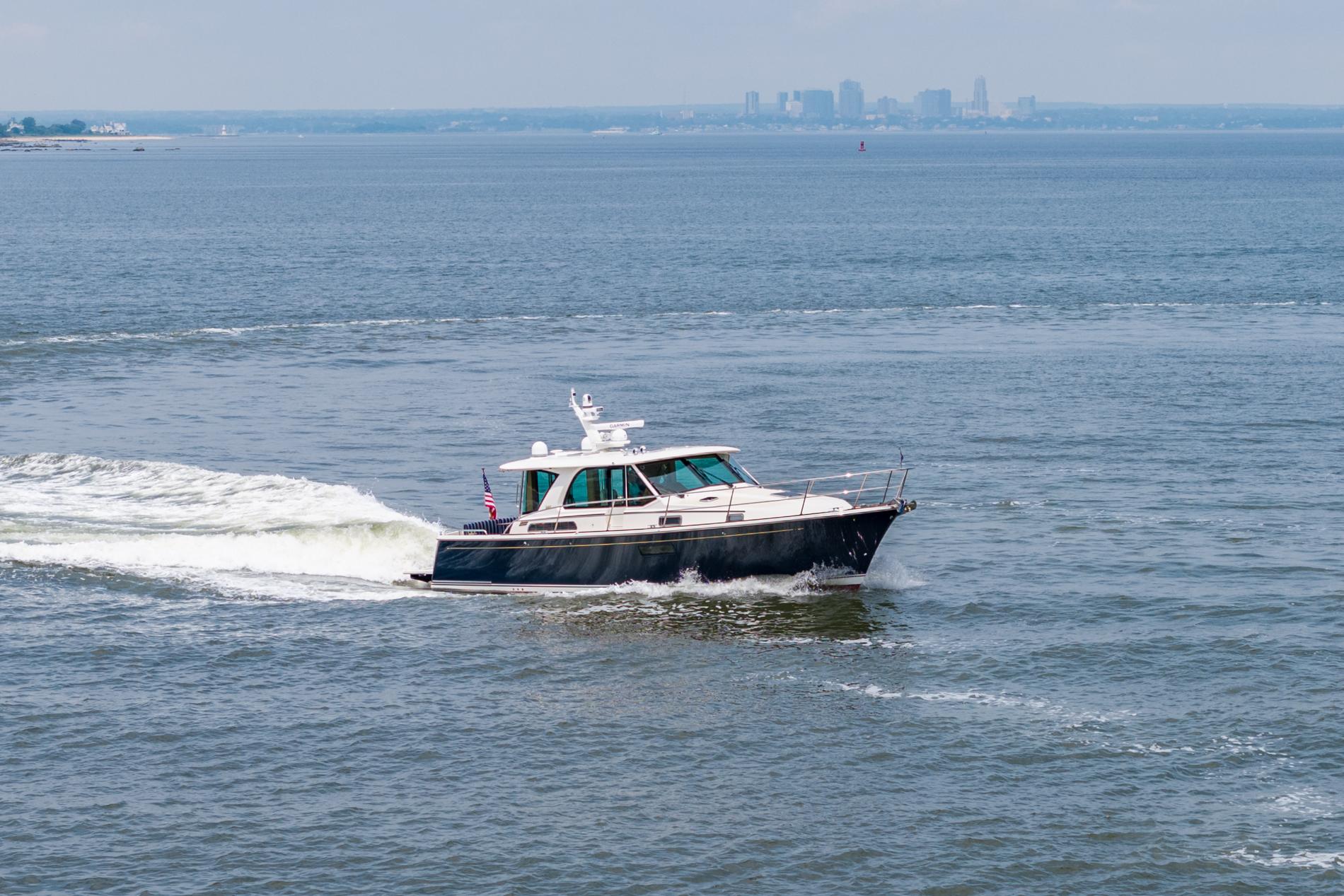 2024 Sabre 43 Salon Express cruising on open water with city skyline in background.