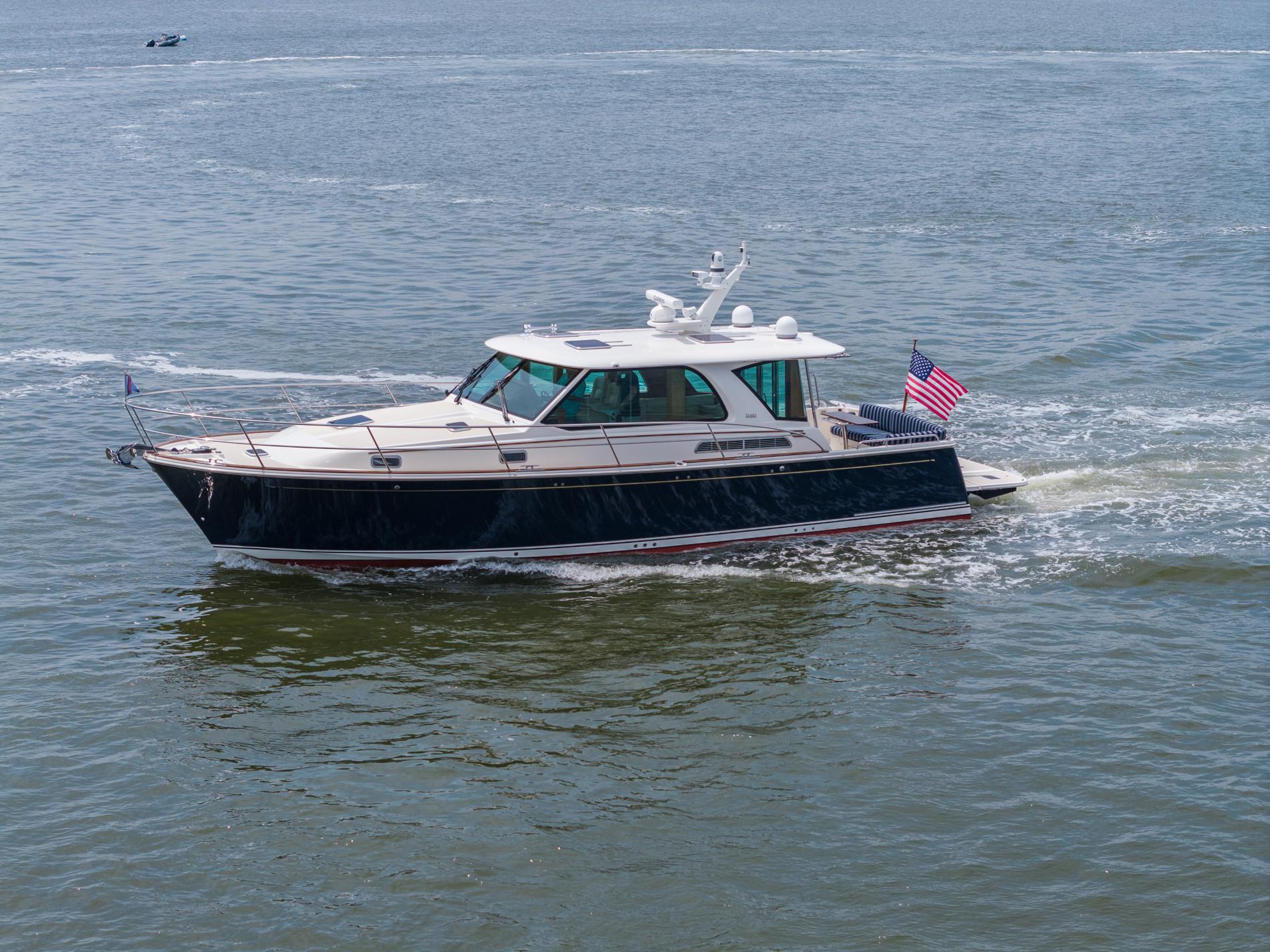 2024 Sabre 43 Salon Express yacht cruising on open water with American flag.