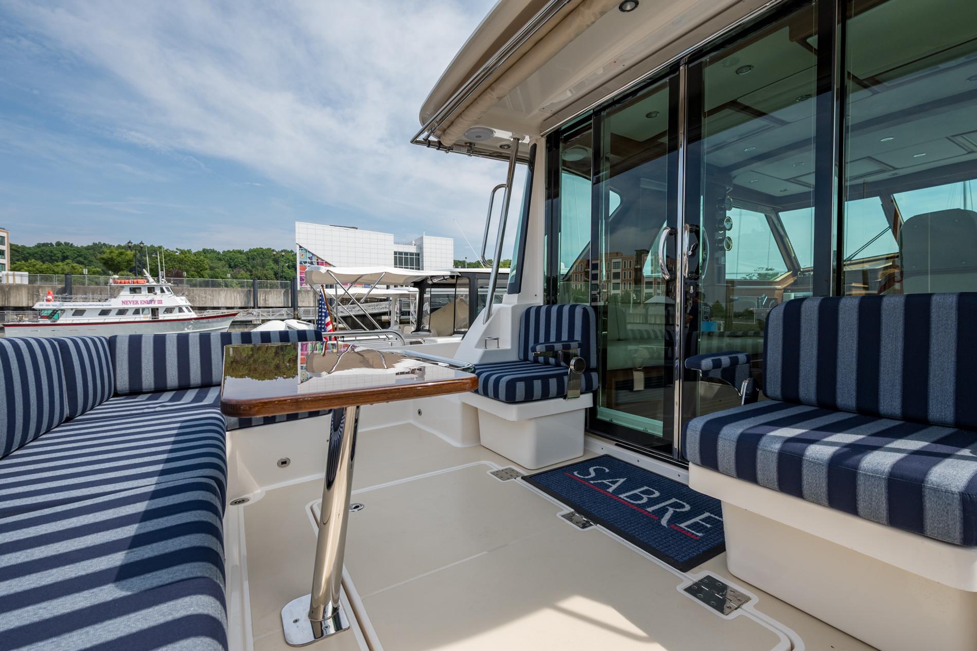 2024 Sabre 43 Salon Express yacht with striped seating and glass doors at a marina.
