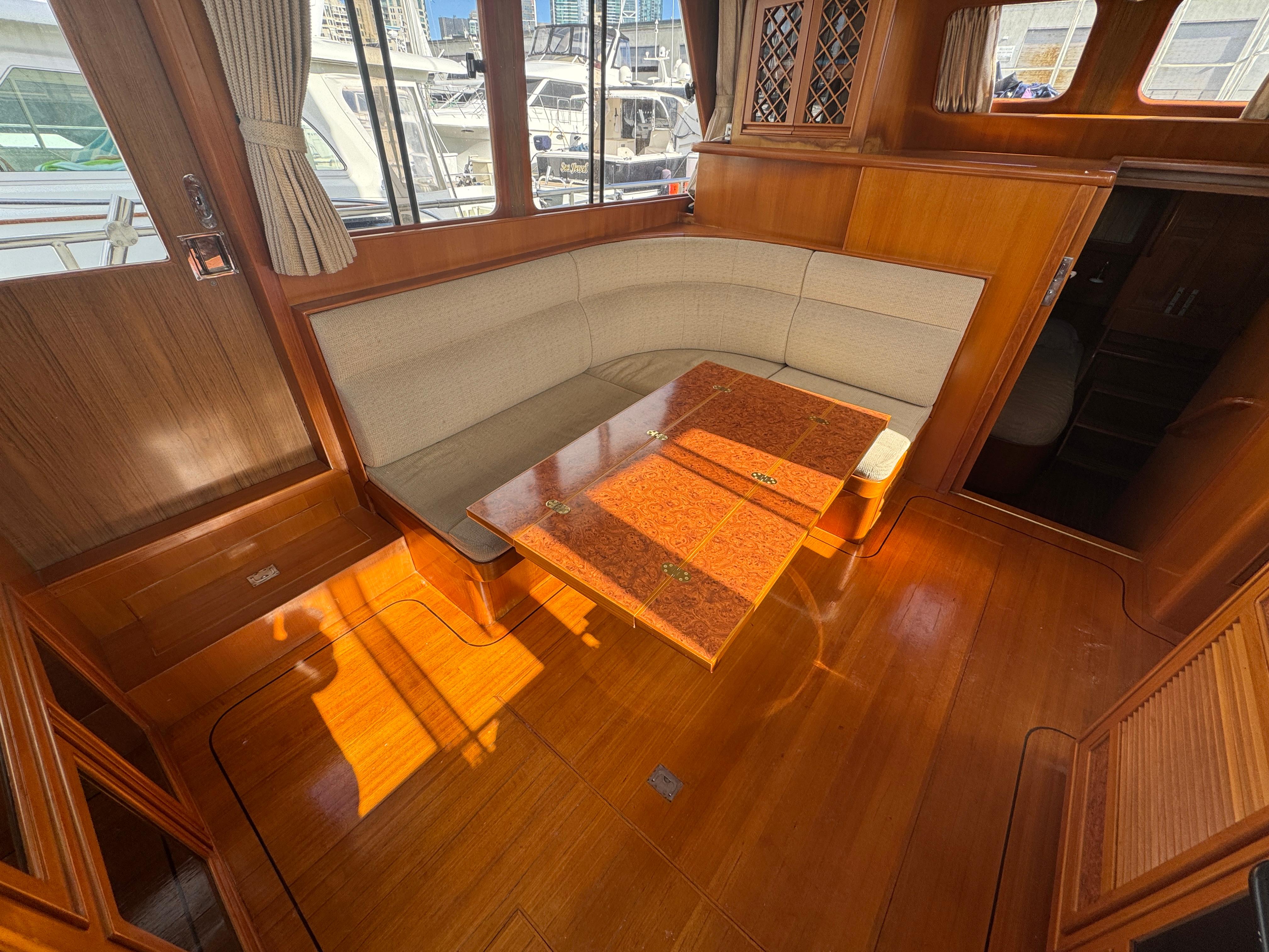 2003 President Performance Trawler interior with wooden flooring and cushioned seating area.