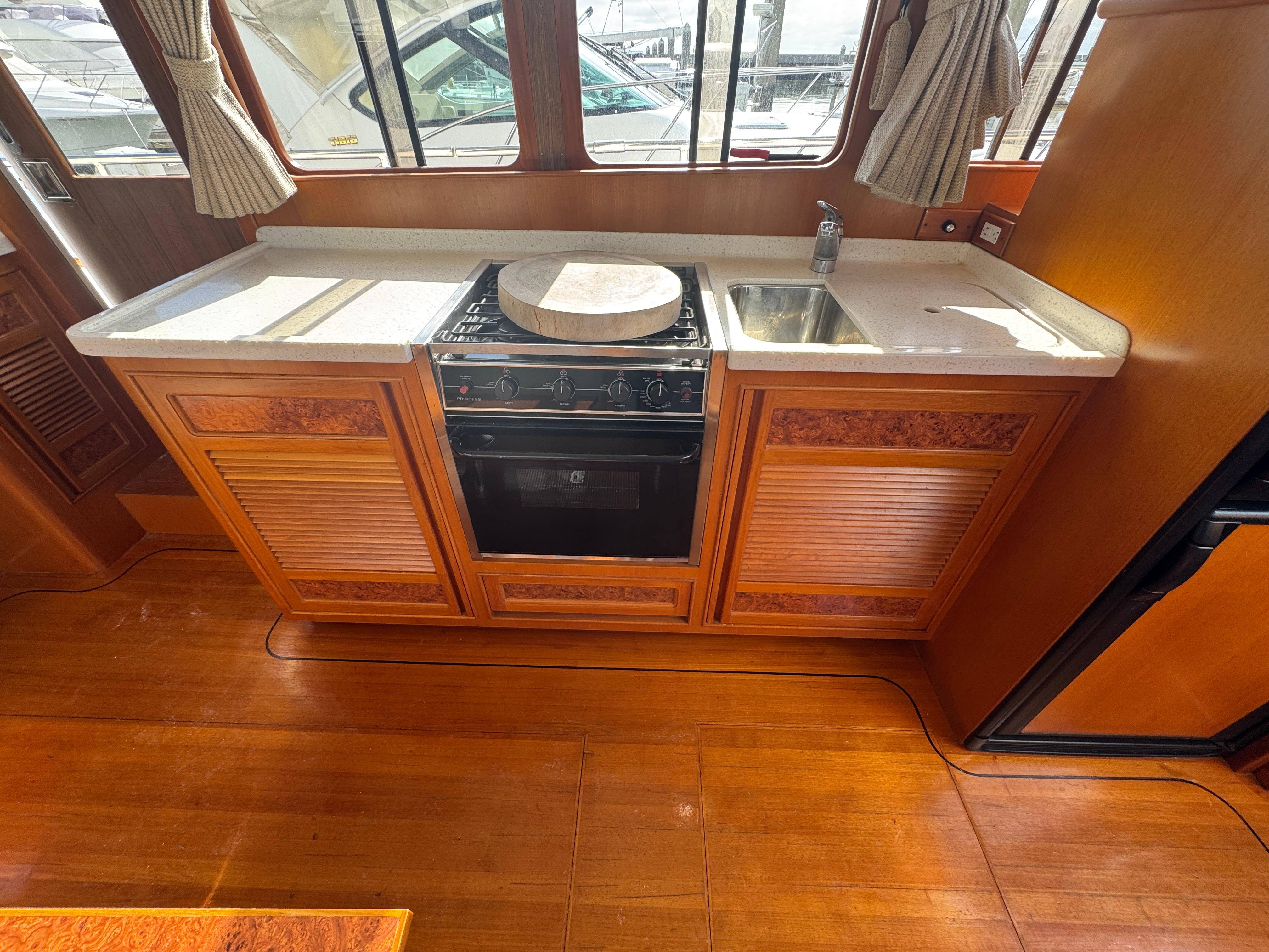 2003 President Performance Trawler kitchen with stove, sink, and wooden cabinetry.