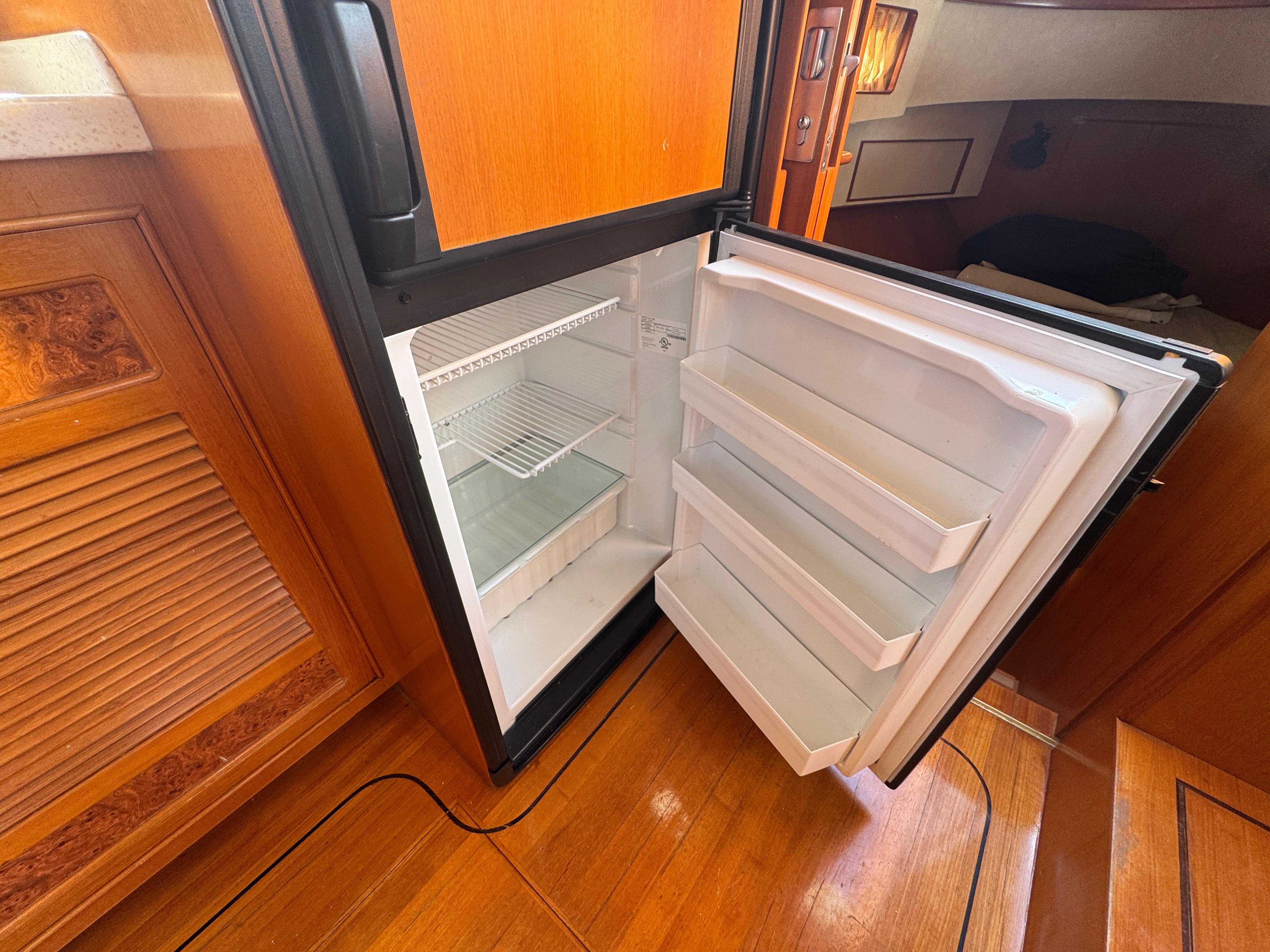 Open refrigerator inside 2003 President Performance Trawler, showcasing wooden interior and storage space.