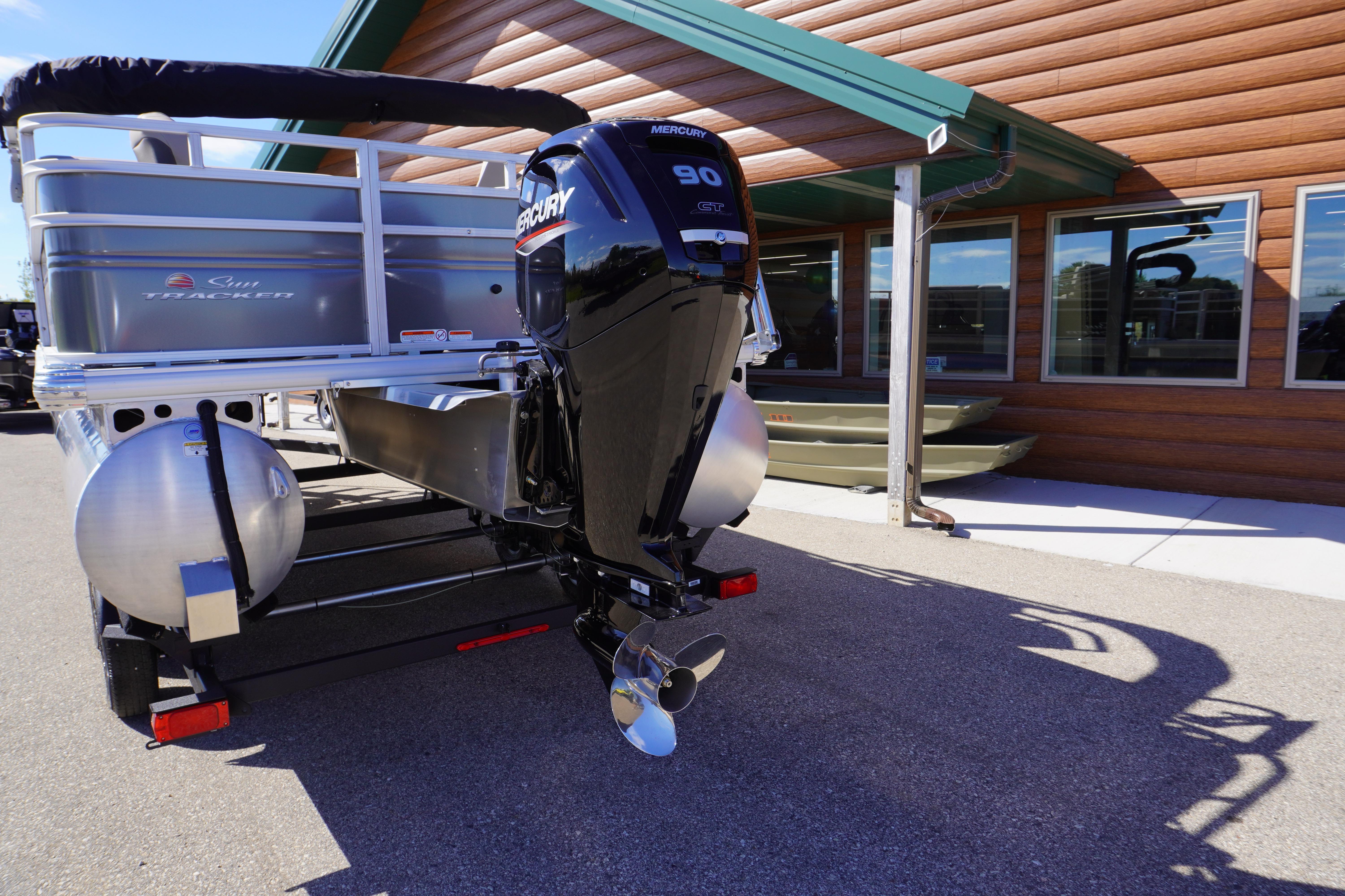 2024 Sun Tracker Fishin' Barge 20 DLX with Mercury 90 engine, parked outside a building.