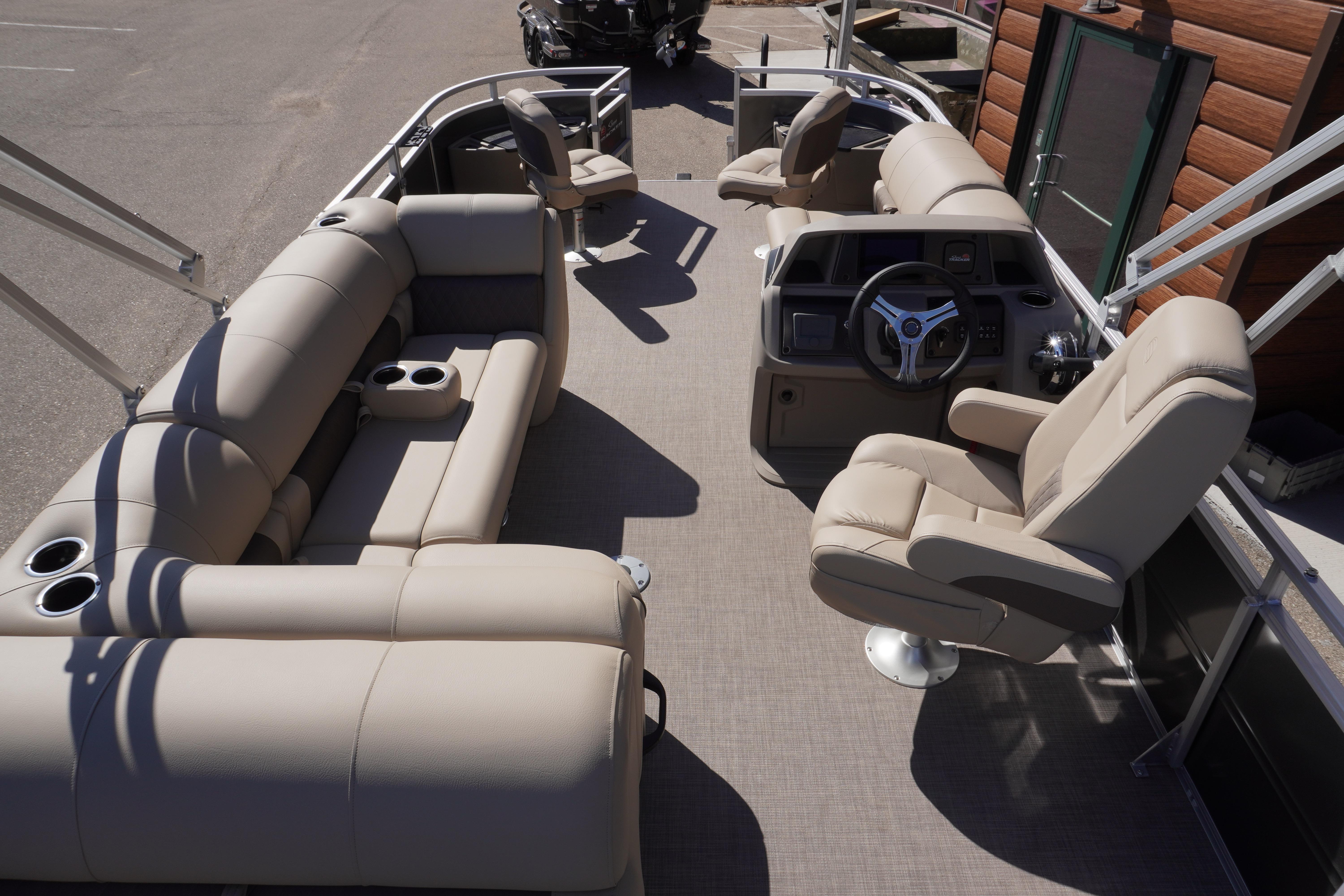 2024 Sun Tracker Fishin' Barge 20 DLX interior with beige seating and steering console.