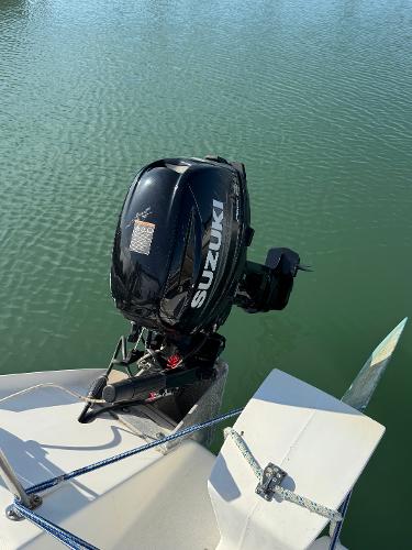 Outboard motor on 1996 Corsair F-31 boat, Suzuki engine, docked on calm water.