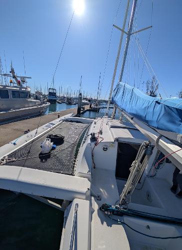 1996 Corsair F-31 sailboat docked in a sunny marina, featuring blue sails and a spacious deck.
