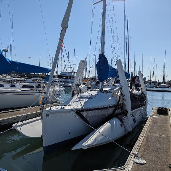 Sailboat docked in marina, Corsair F-31, 1996 model, with blue covers and clear sky.