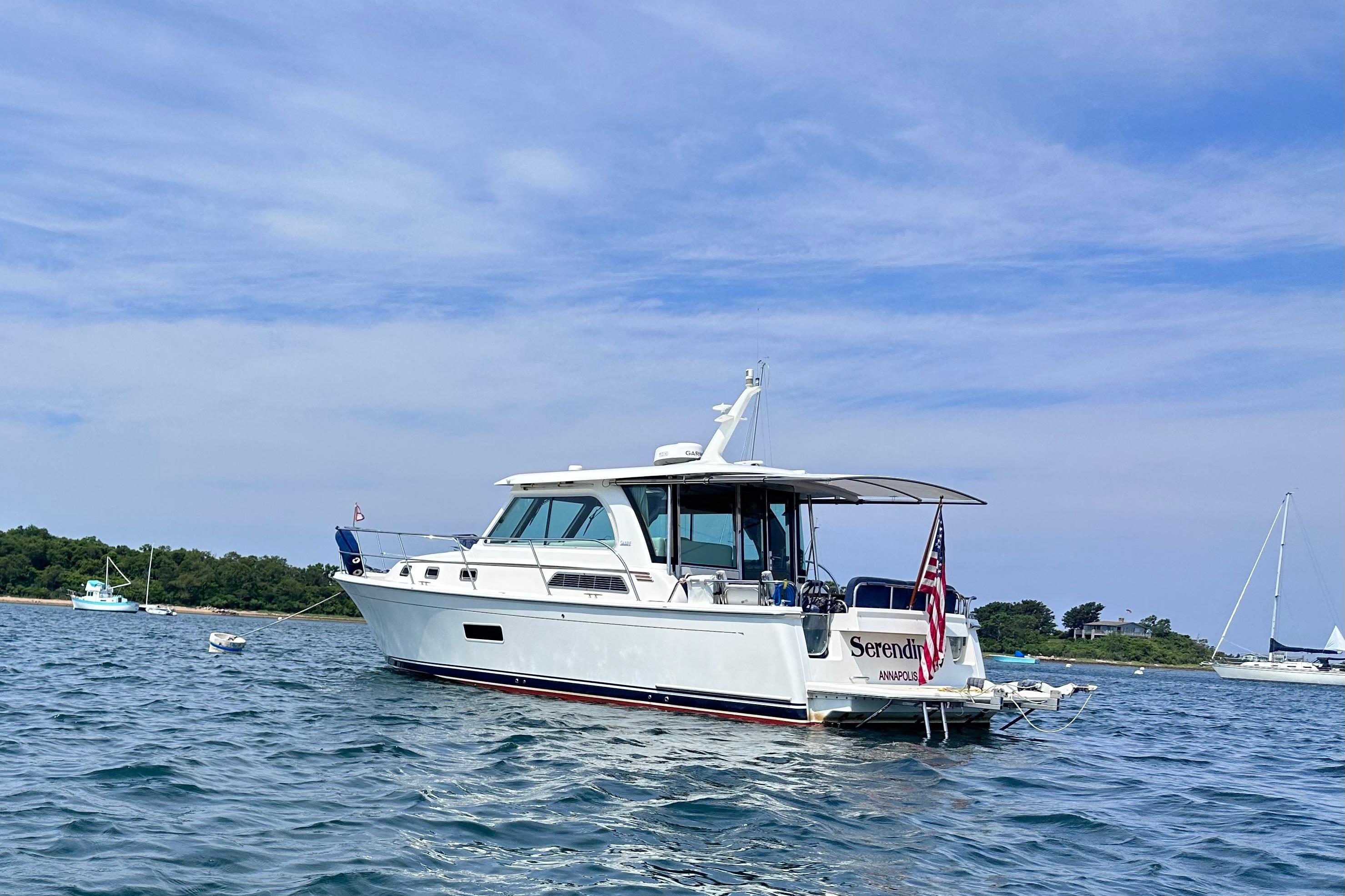 2019 Sabre 38 Salon Express yacht on calm water with scenic background.