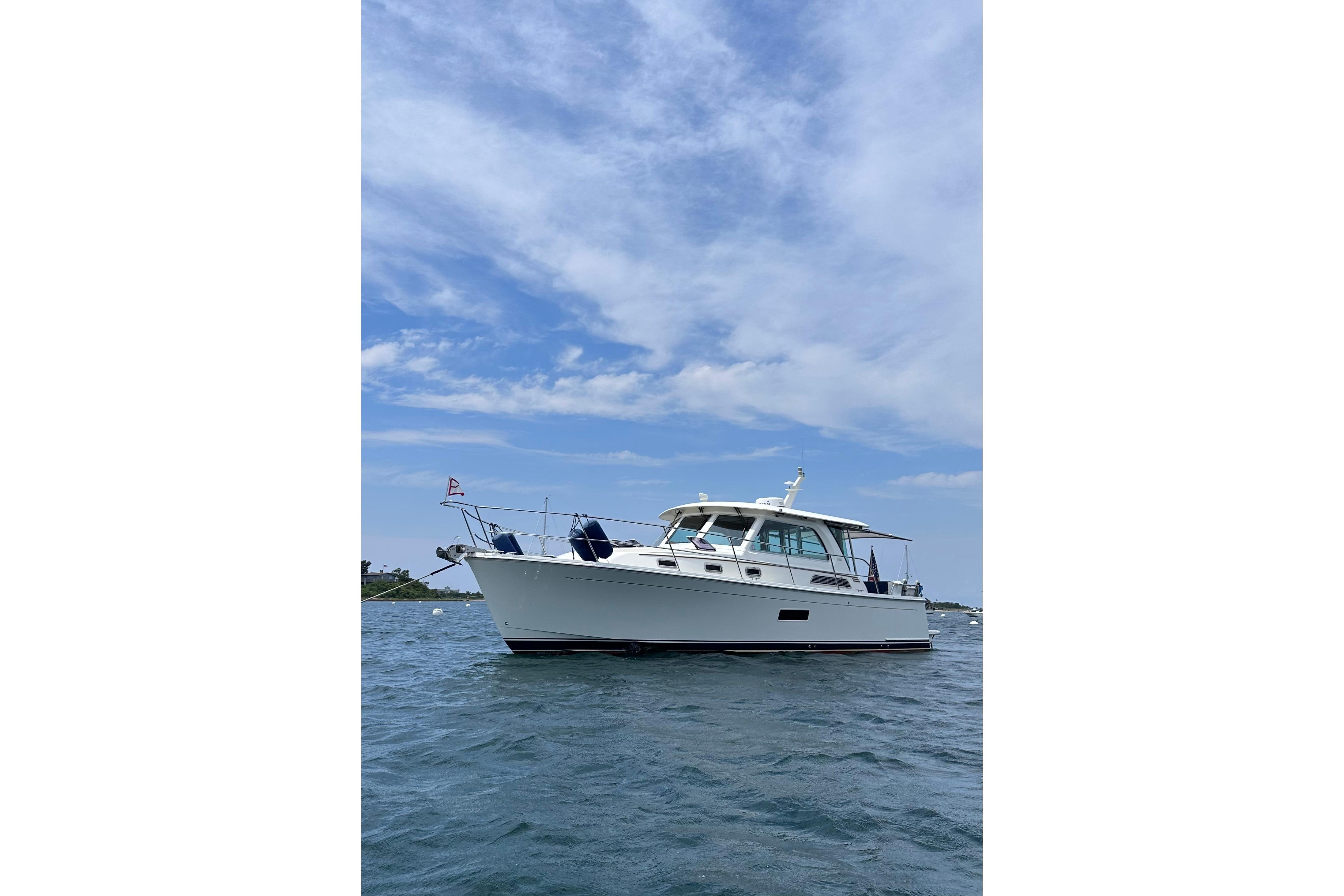 2019 Sabre 38 Salon Express yacht on calm water under a blue sky.
