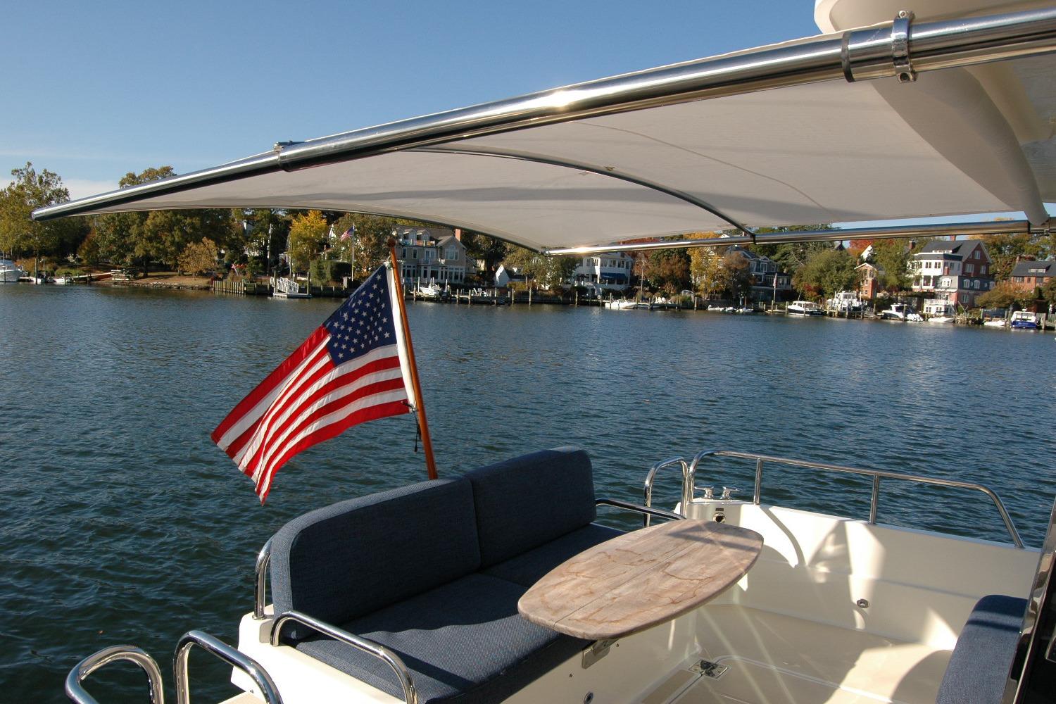 2019 Sabre 38 Salon Express yacht with American flag, scenic waterfront view.