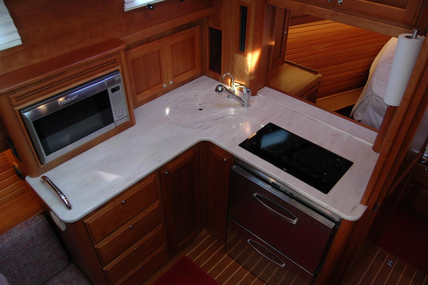 2019 Sabre 38 Salon Express galley with stove, microwave, and wooden cabinetry.