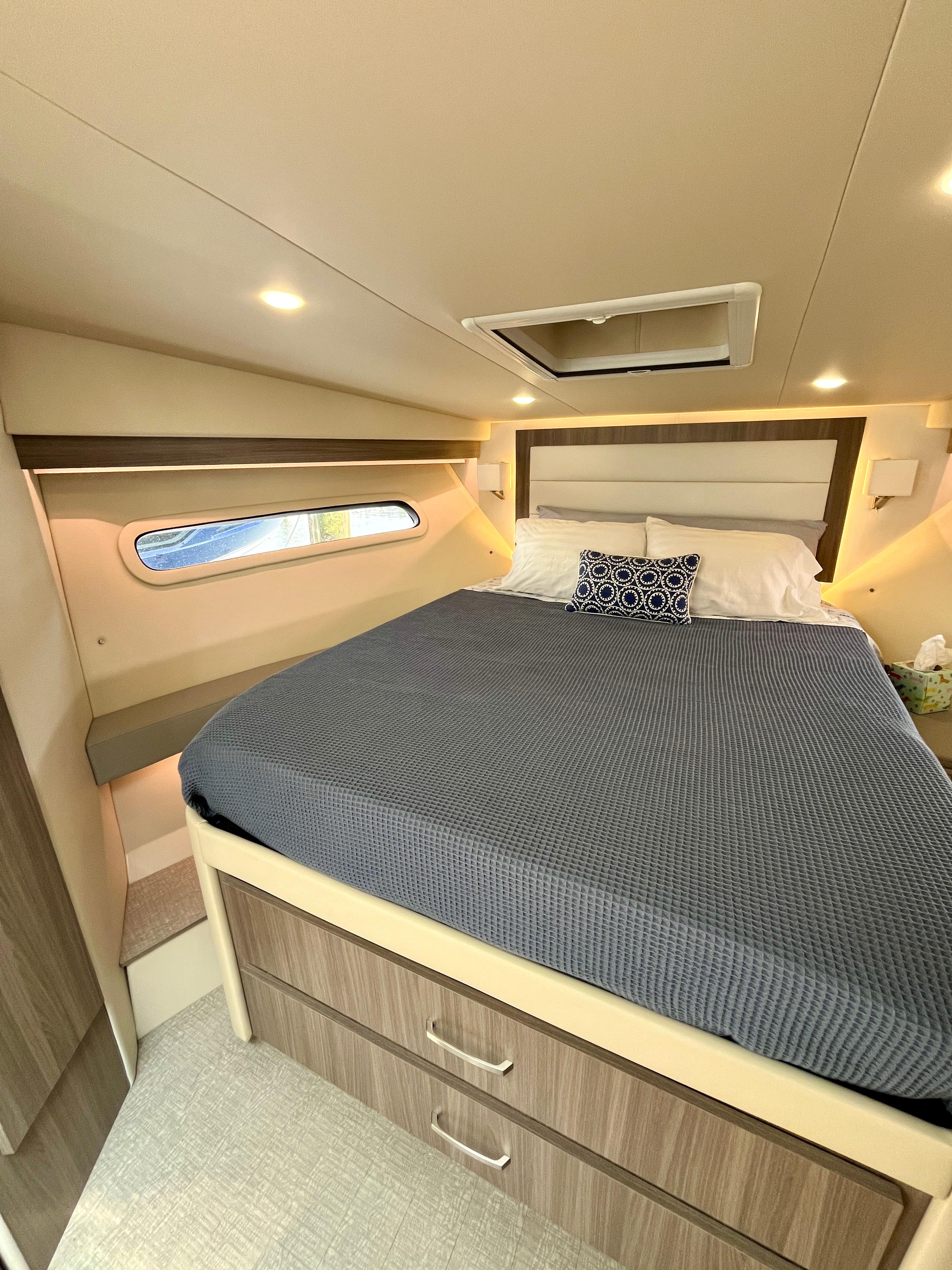 Luxurious bedroom interior of 2022 Regal 38 XO yacht with modern design and cozy bedding.