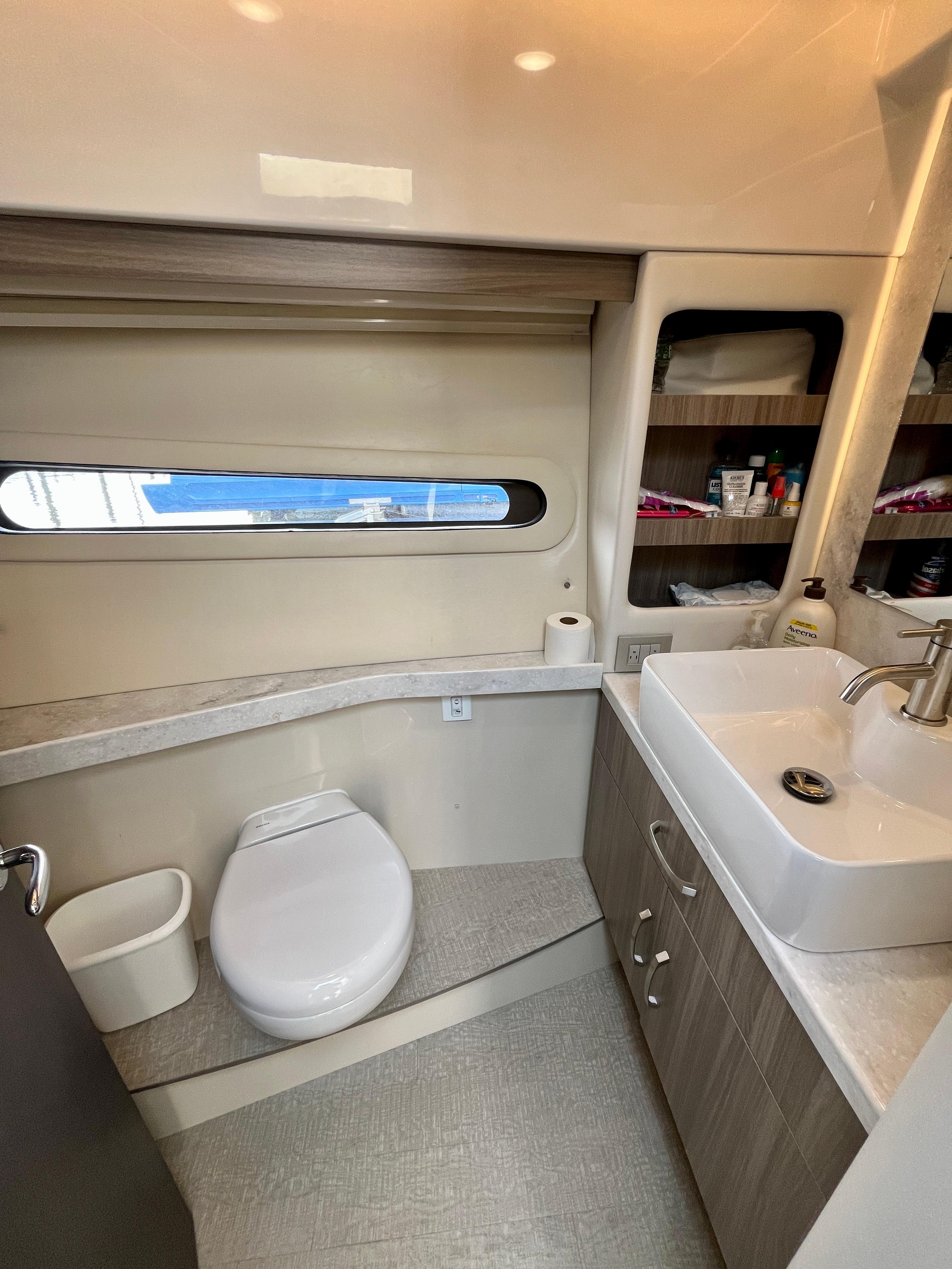 2022 Regal 38 XO yacht bathroom with modern sink, toilet, and storage shelves.