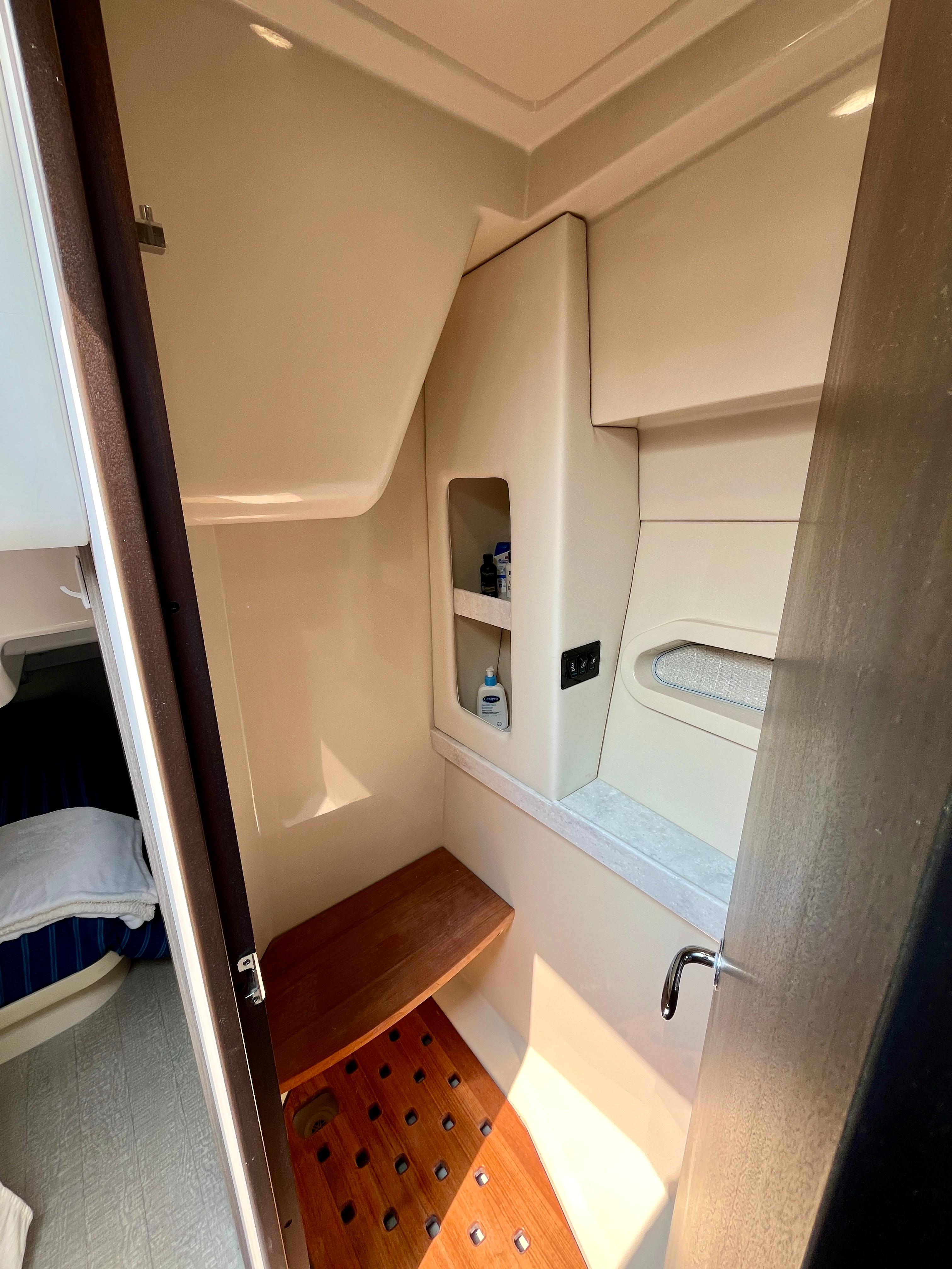 2022 Regal 38 XO yacht bathroom with wooden bench and storage shelves.