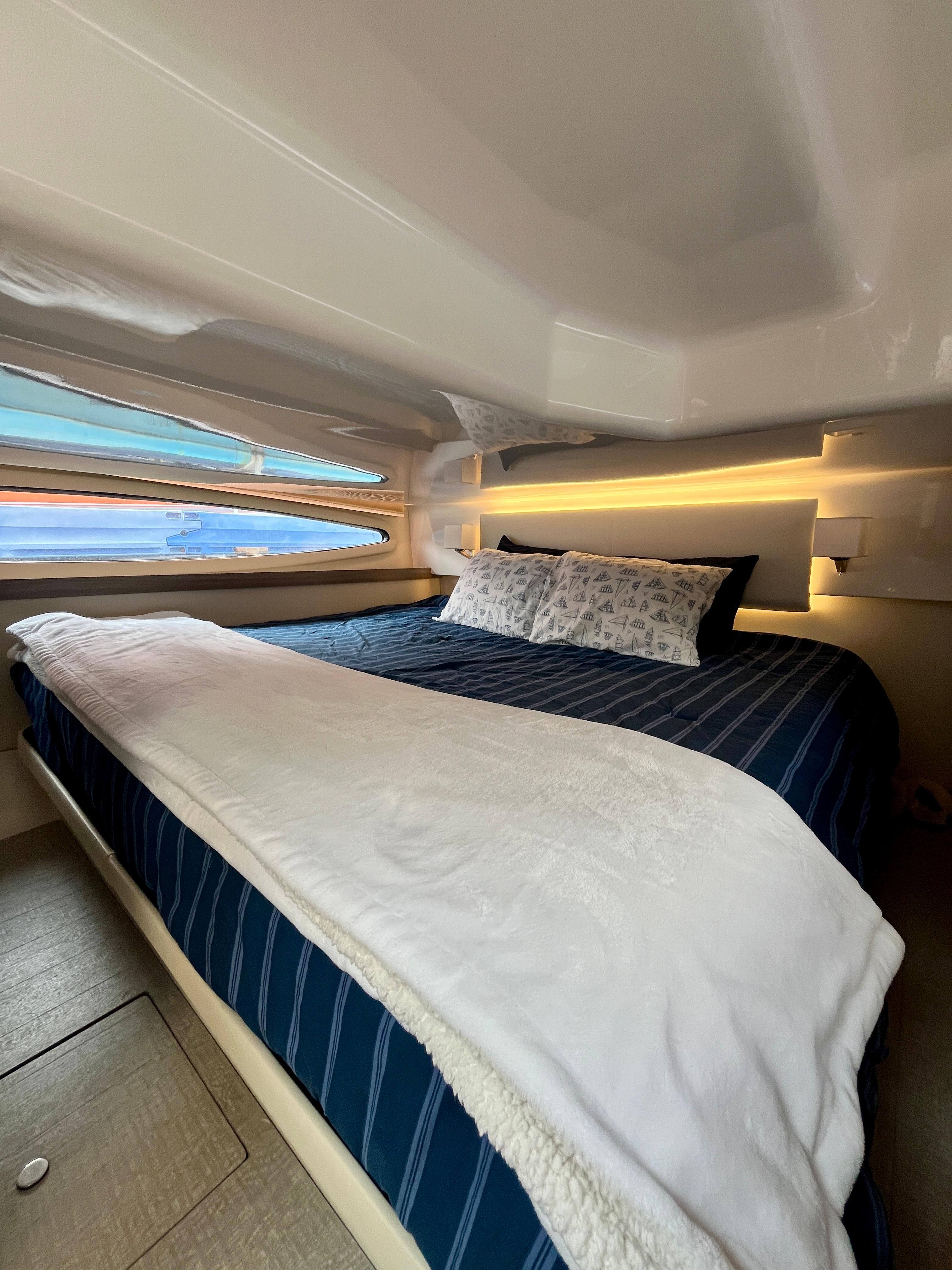 Luxurious cabin interior of 2022 Regal 38 XO yacht with cozy bedding and ambient lighting.