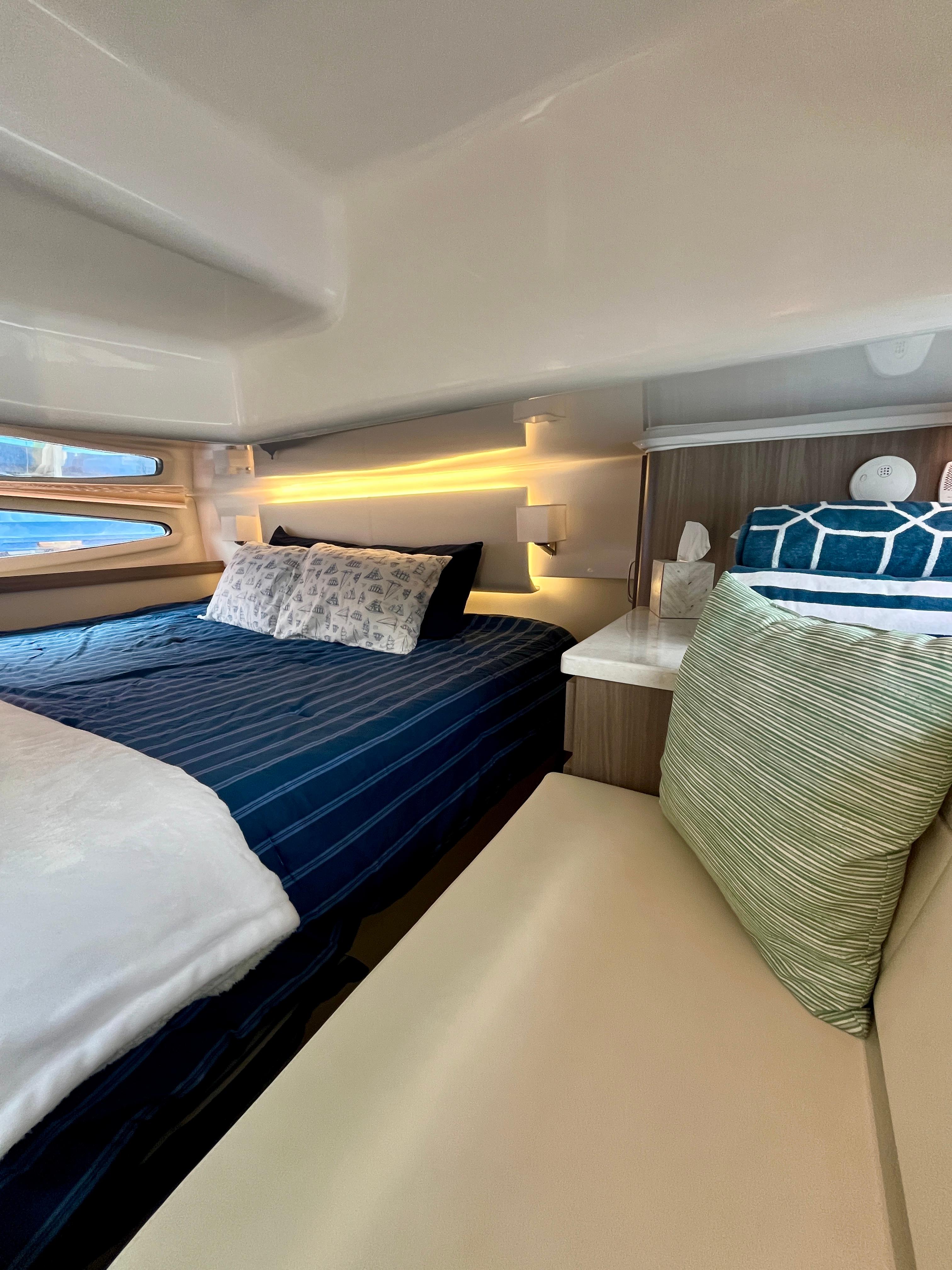 Luxurious cabin interior of 2022 Regal 38 XO yacht with cozy bedding and ambient lighting.