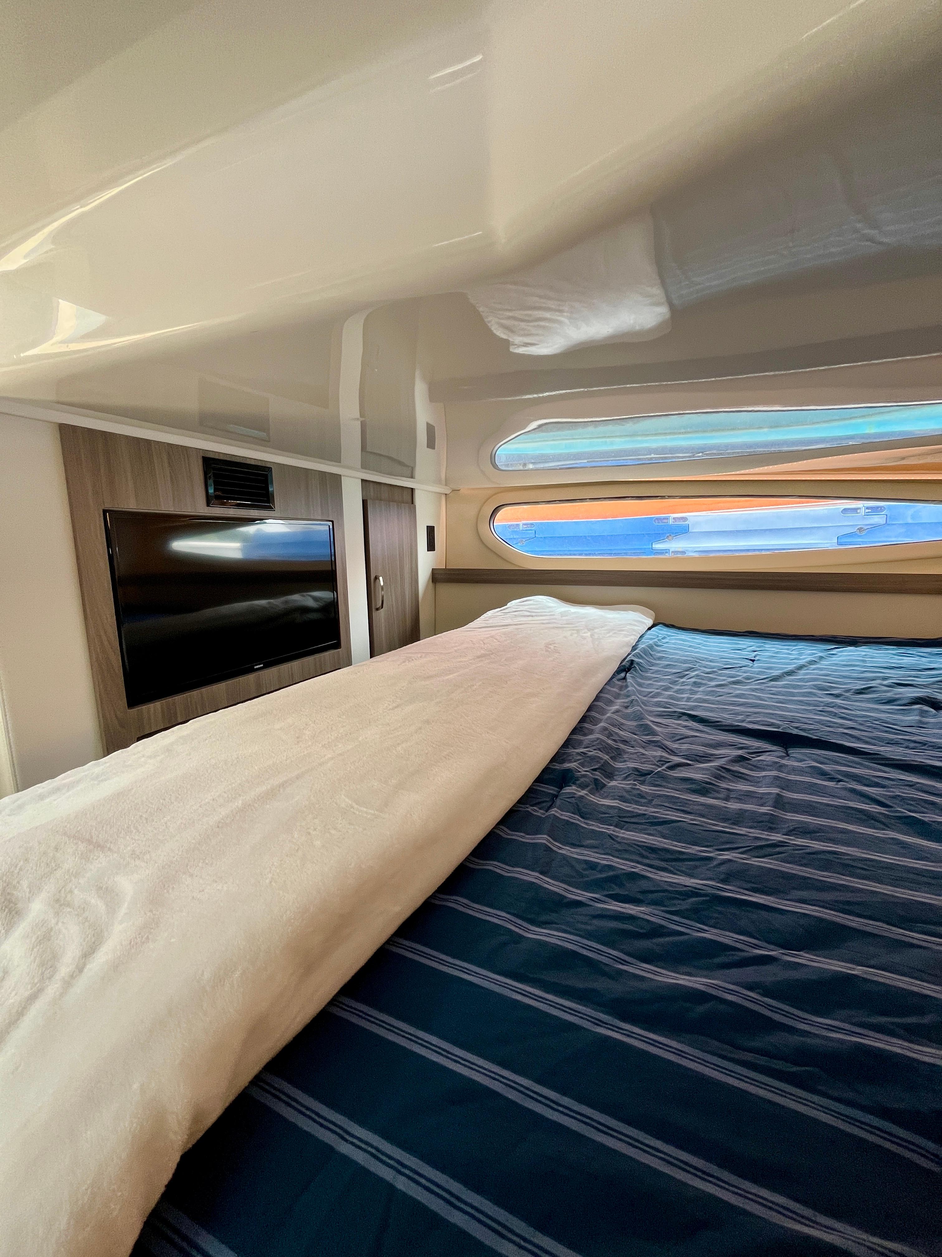 Luxurious cabin interior of 2022 Regal 38 XO yacht with bed and TV.