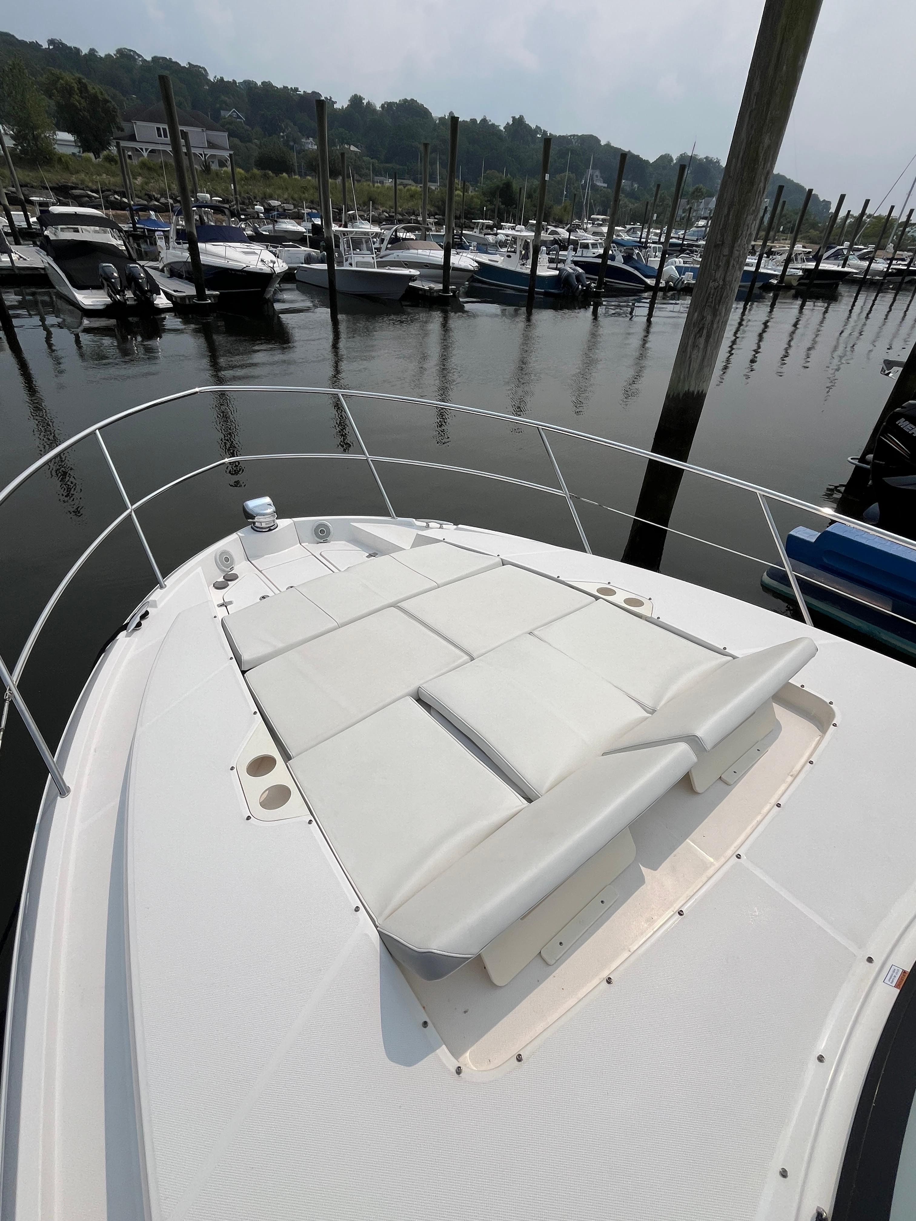 Bow view of 2022 Regal 38 XO yacht with sunpad, docked in marina.