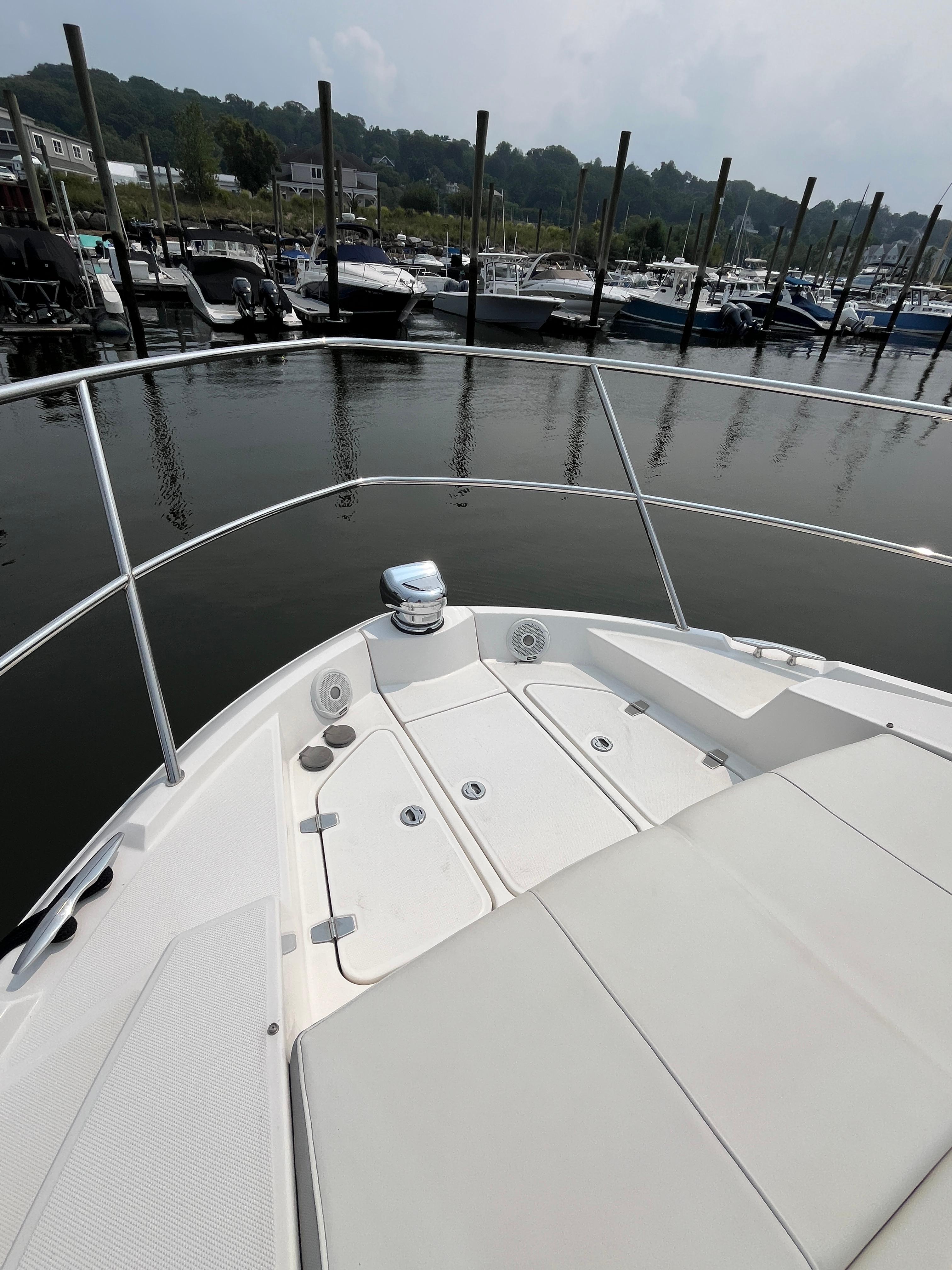 Bow of 2022 Regal 38 XO yacht docked at marina, featuring sleek design and spacious deck.