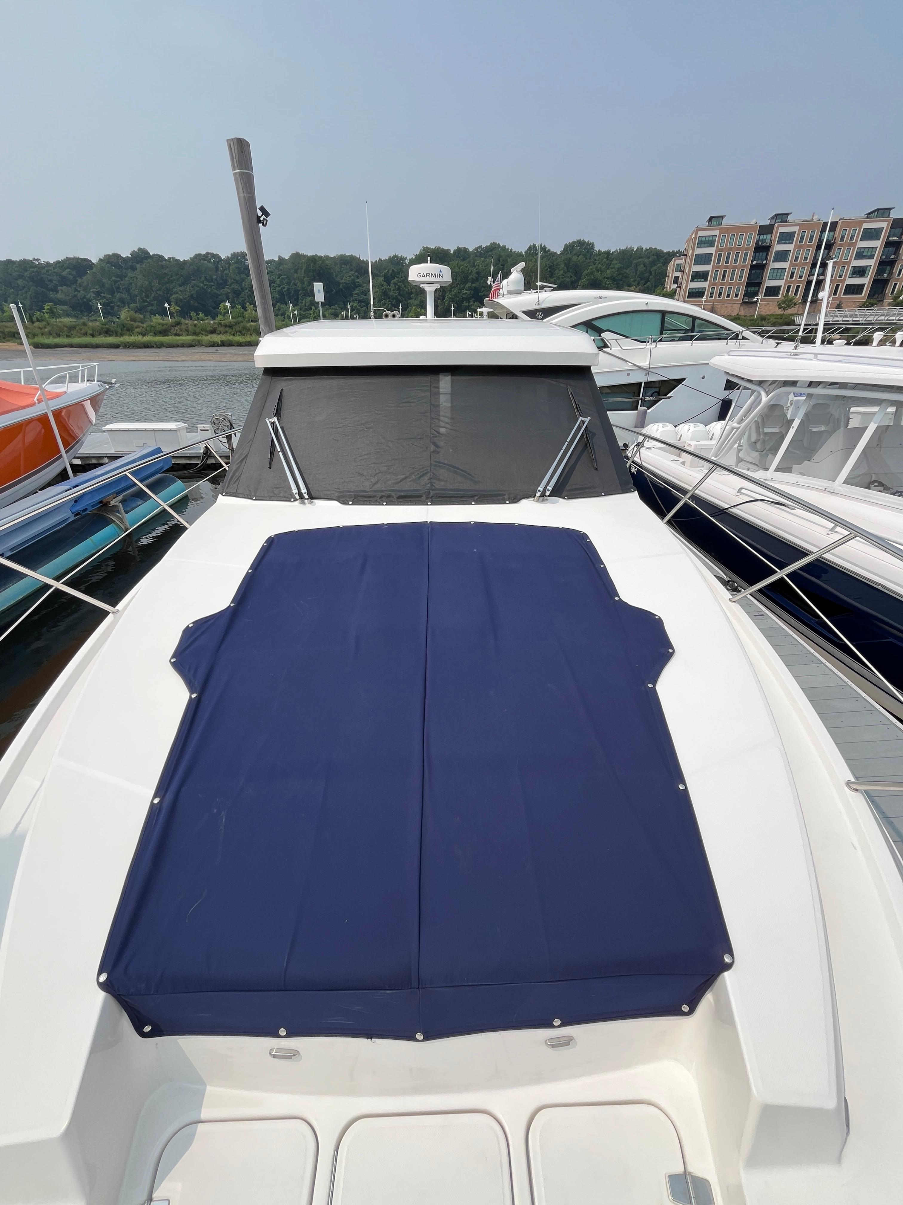2022 Regal 38 XO yacht with blue cover docked at marina.