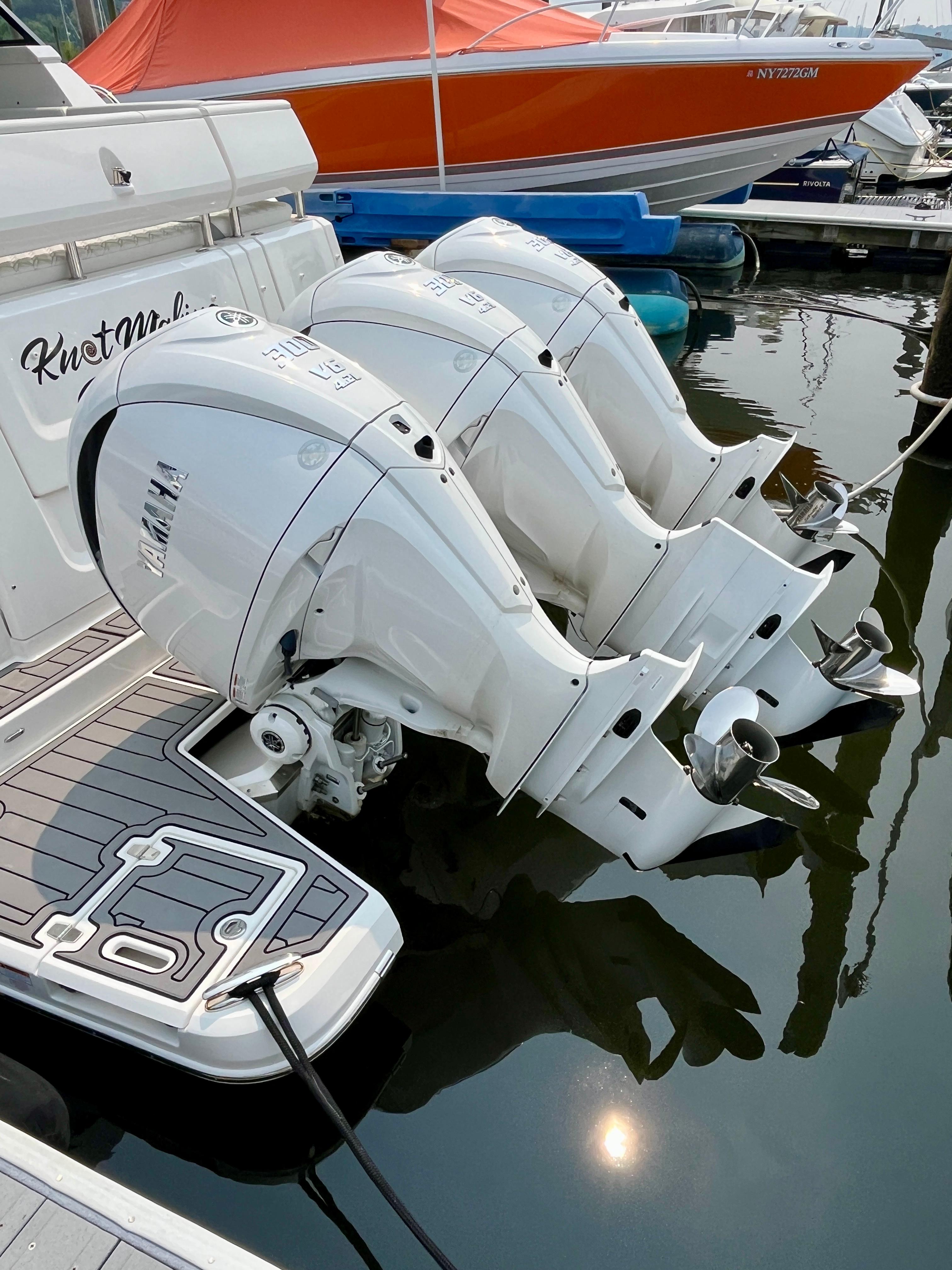 2022 Regal 38 XO boat with triple outboard engines docked in marina.