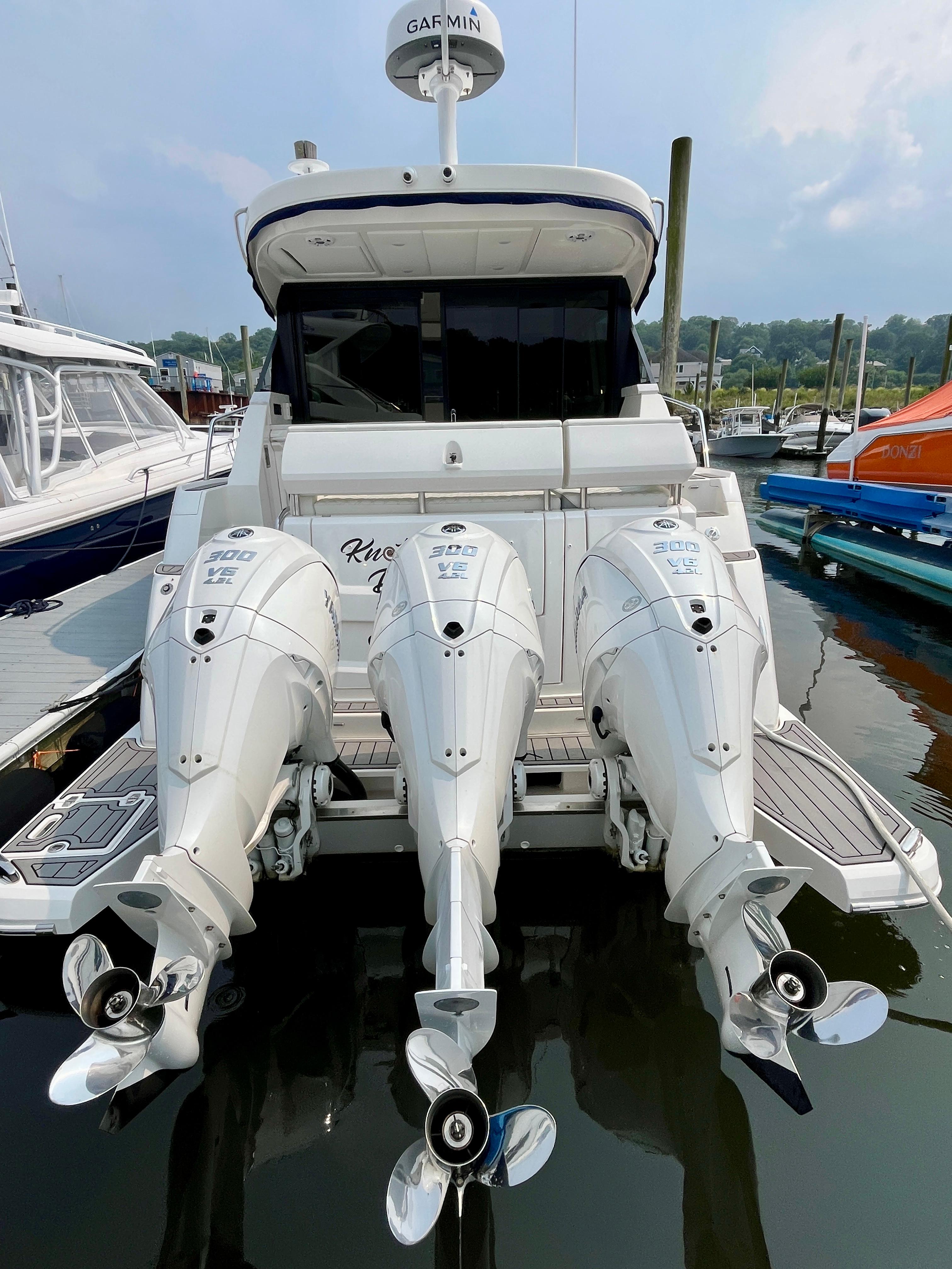 2022 Regal 38 XO boat with triple outboard engines docked at marina.