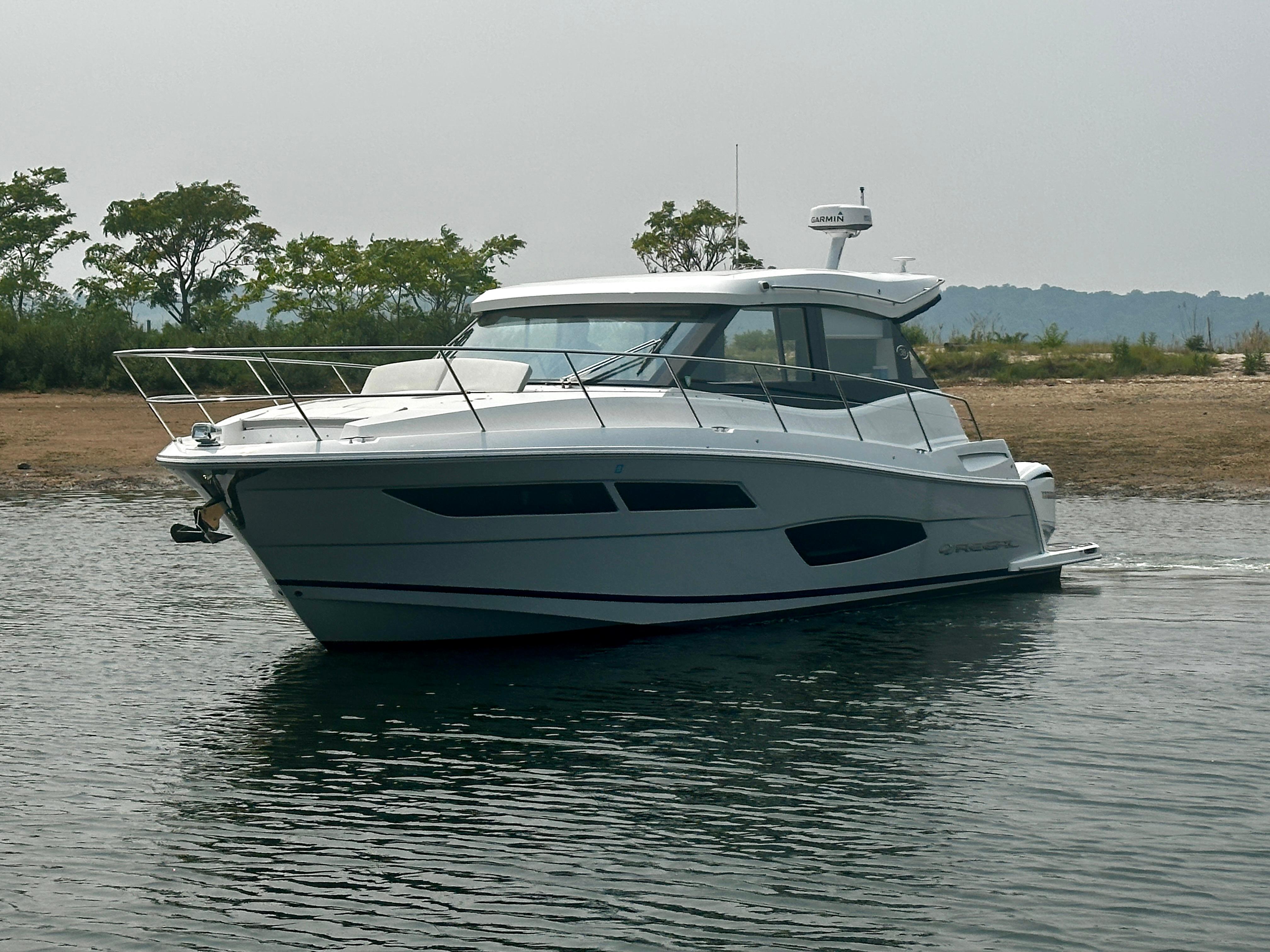2022 Regal 38 XO yacht on calm water near a sandy shore.