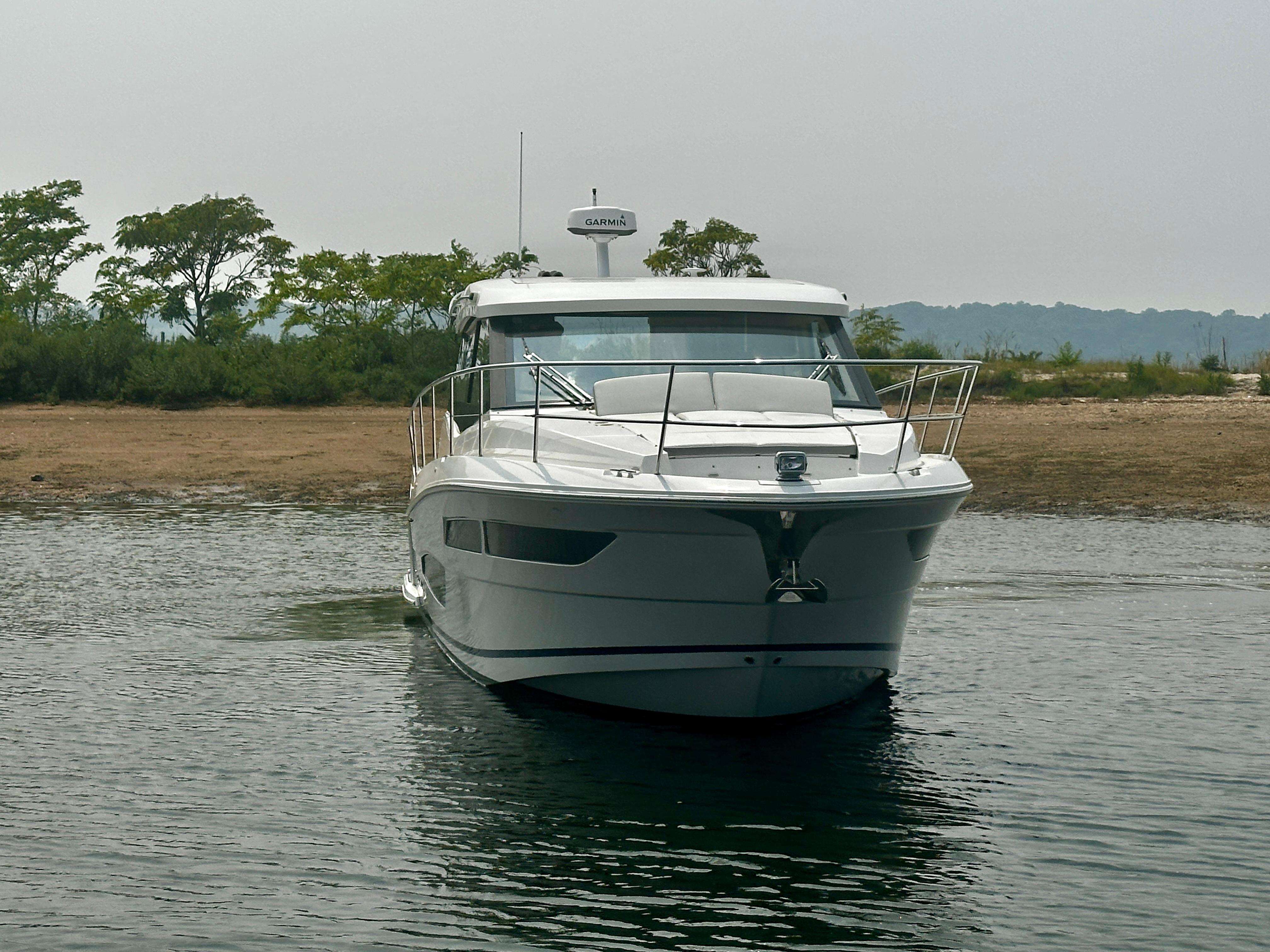 2022 Regal 38 XO yacht on calm water near a shoreline.