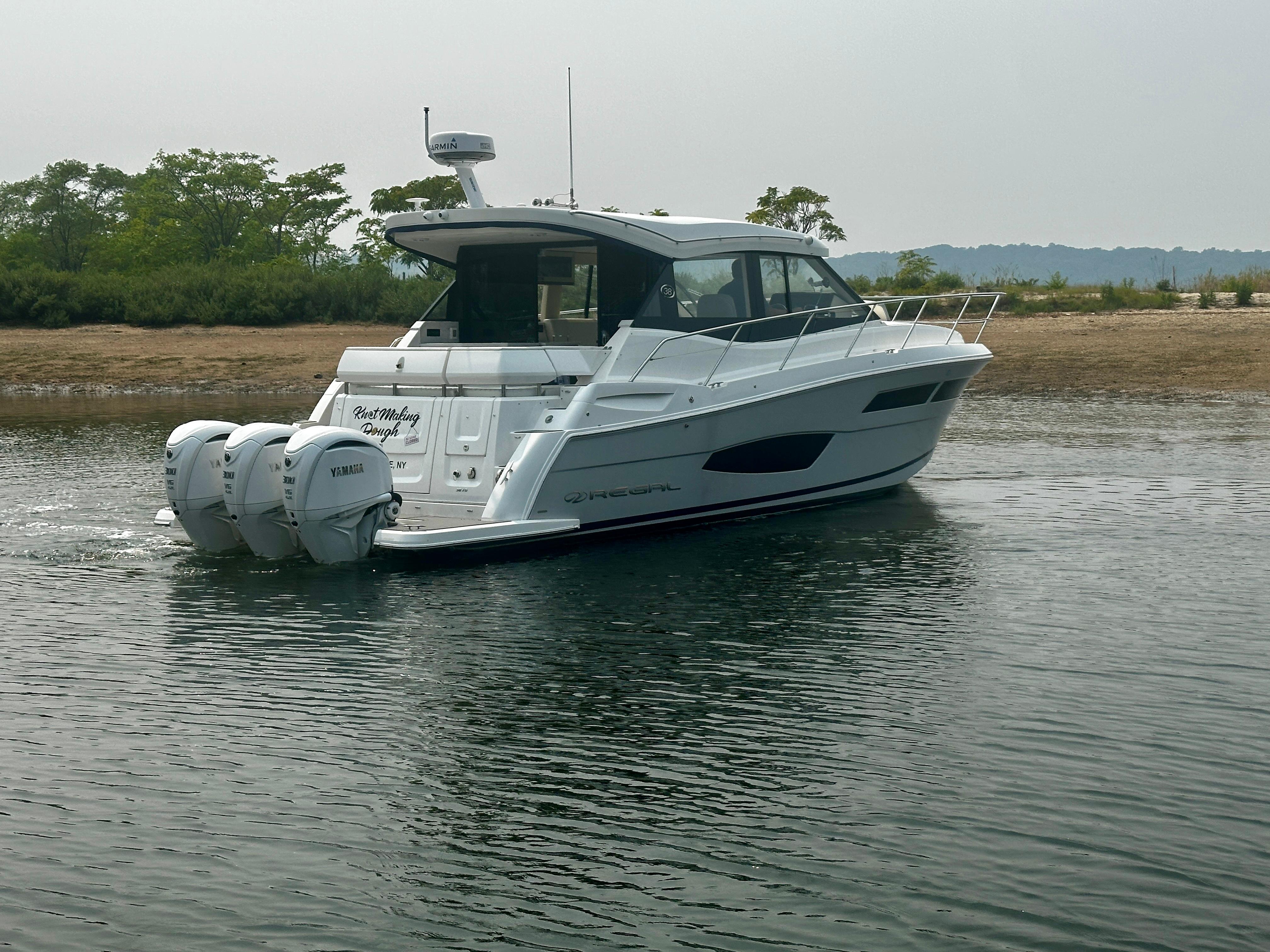 2022 Regal 38 XO boat with triple Yamaha engines on calm water.