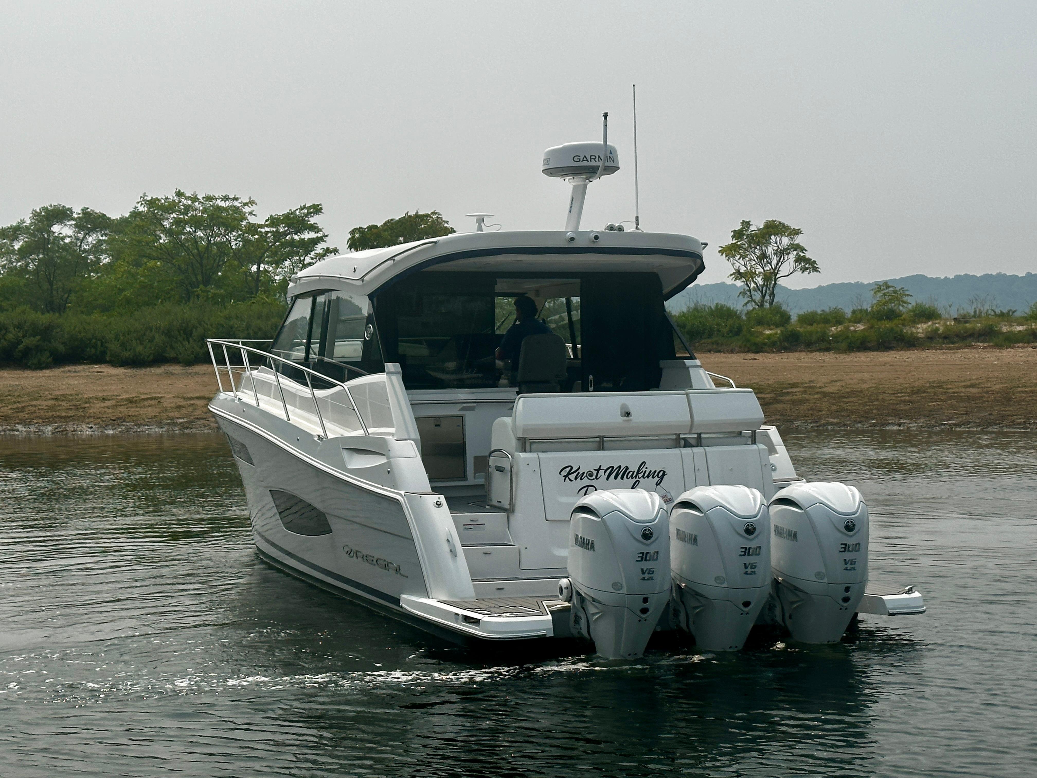 2022 Regal 38 XO boat with triple Yamaha engines on calm water.