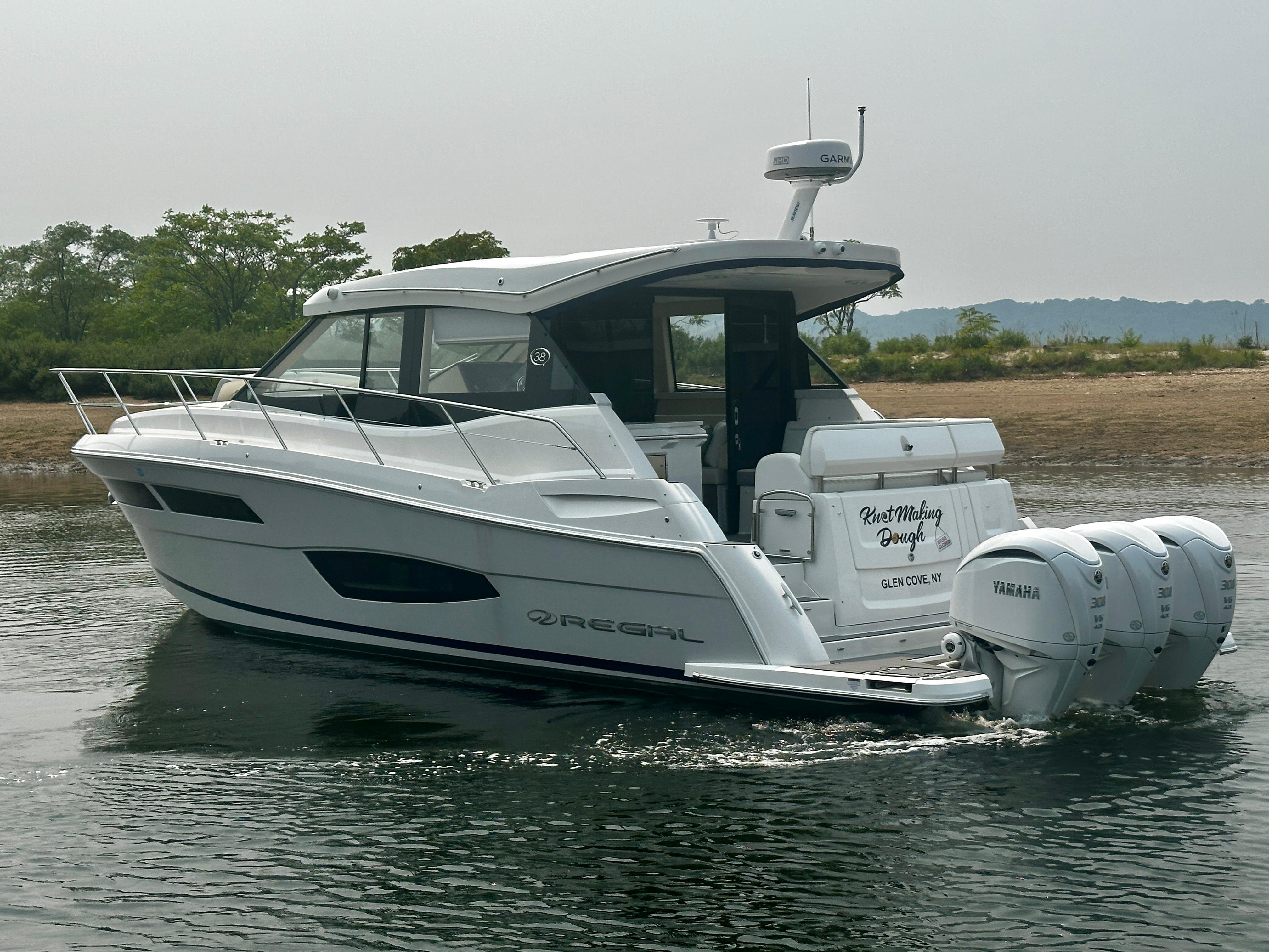 2022 Regal 38 XO boat cruising on water with triple Yamaha engines.