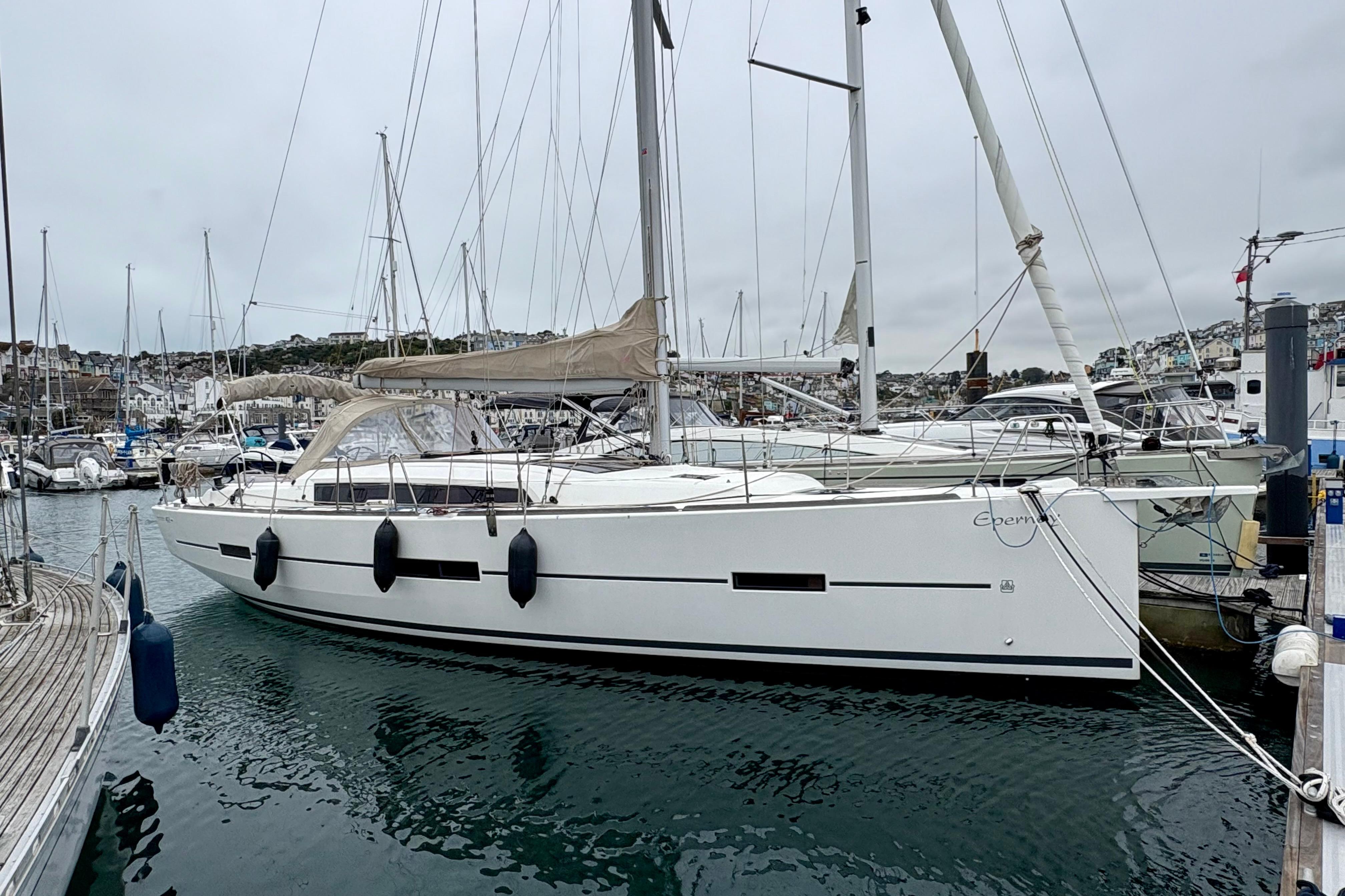 2018 Dufour 412 Grand Large sailboat docked in a marina, overcast sky.