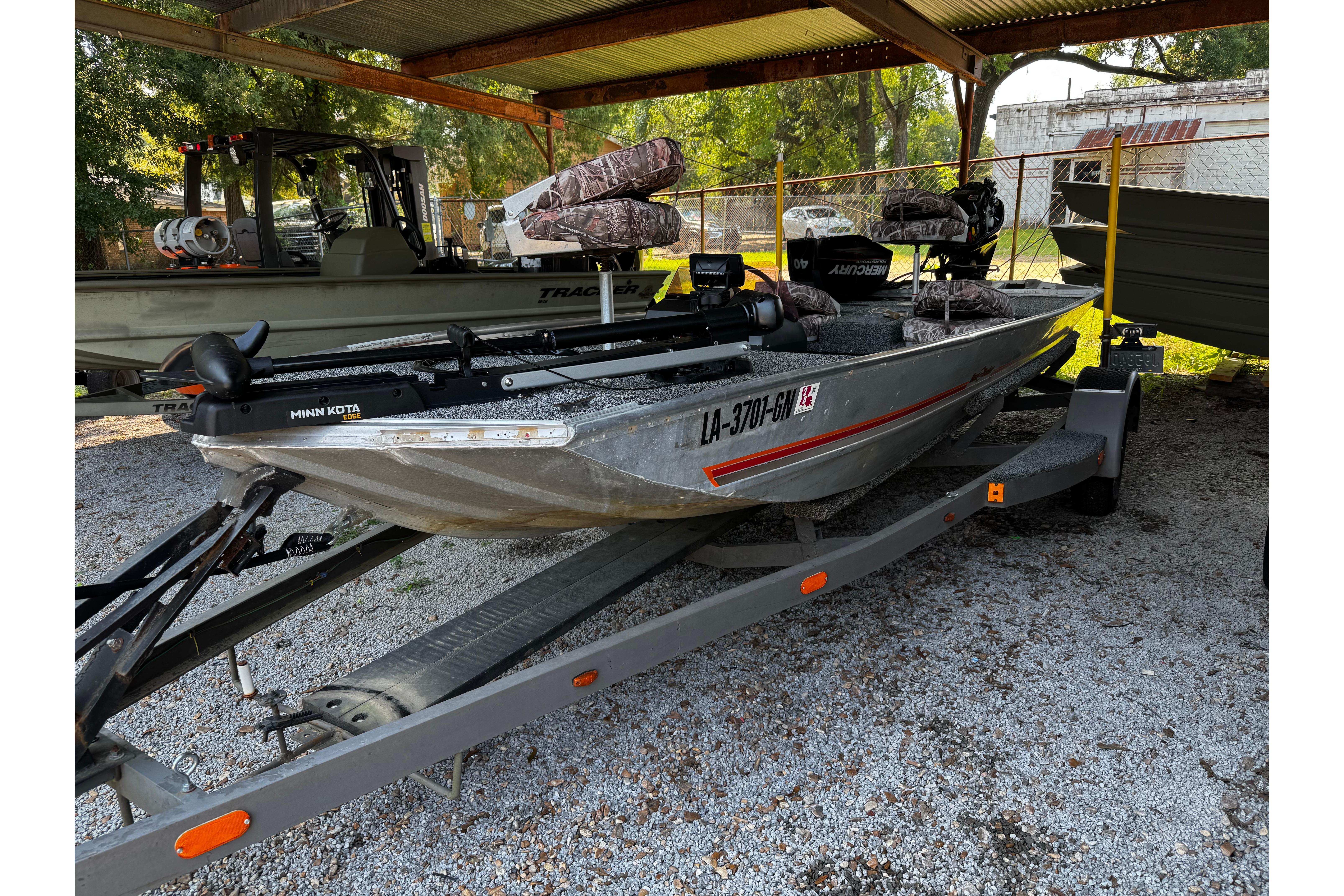 1983 Bass Tracker TOURNAMENT TX fishing boat on trailer under shelter.