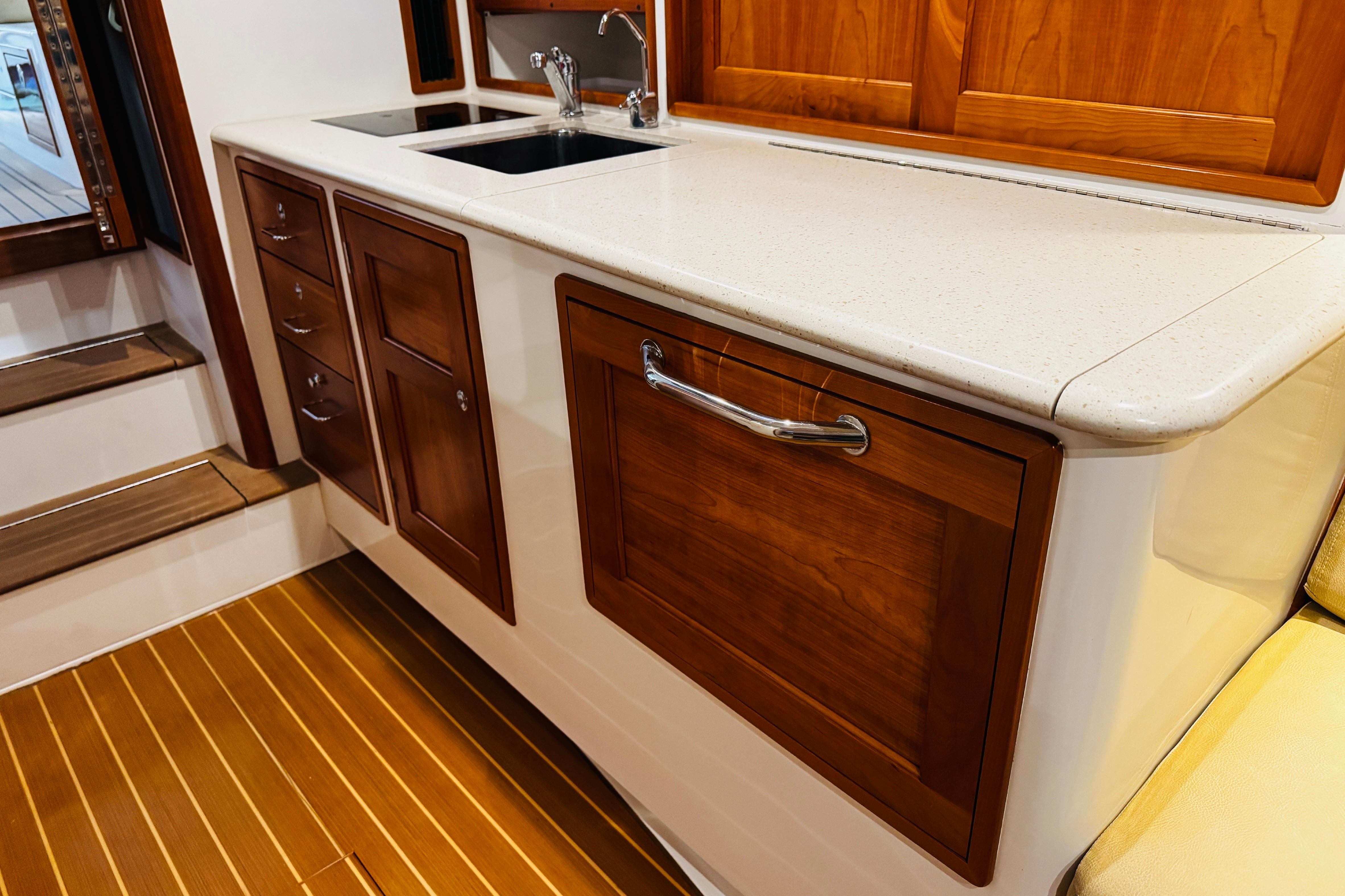 Luxurious galley interior of 2015 MJM 36z Express yacht with wooden cabinetry and modern sink.