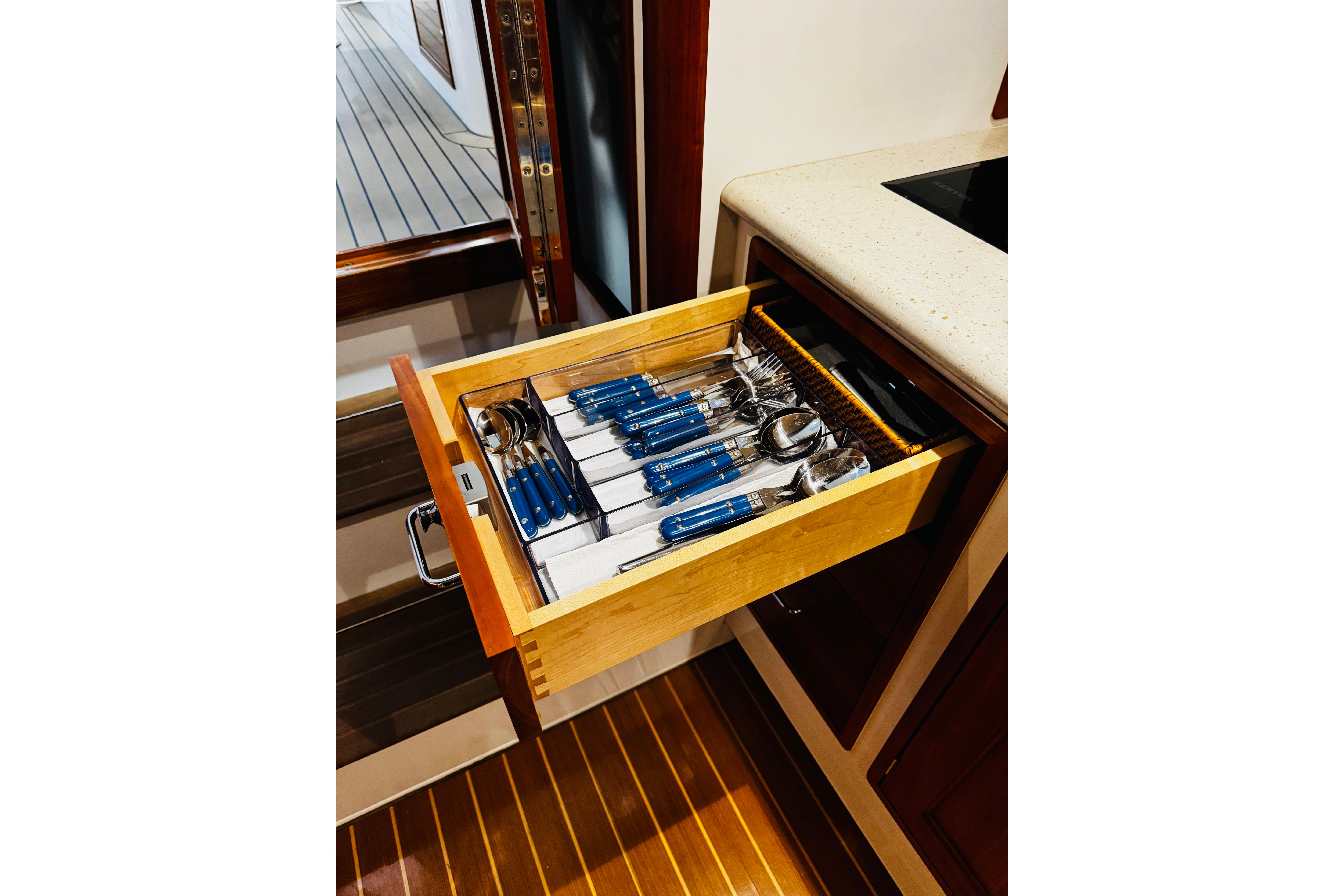 Open drawer with blue-handled cutlery on 2015 MJM 36z Express yacht.