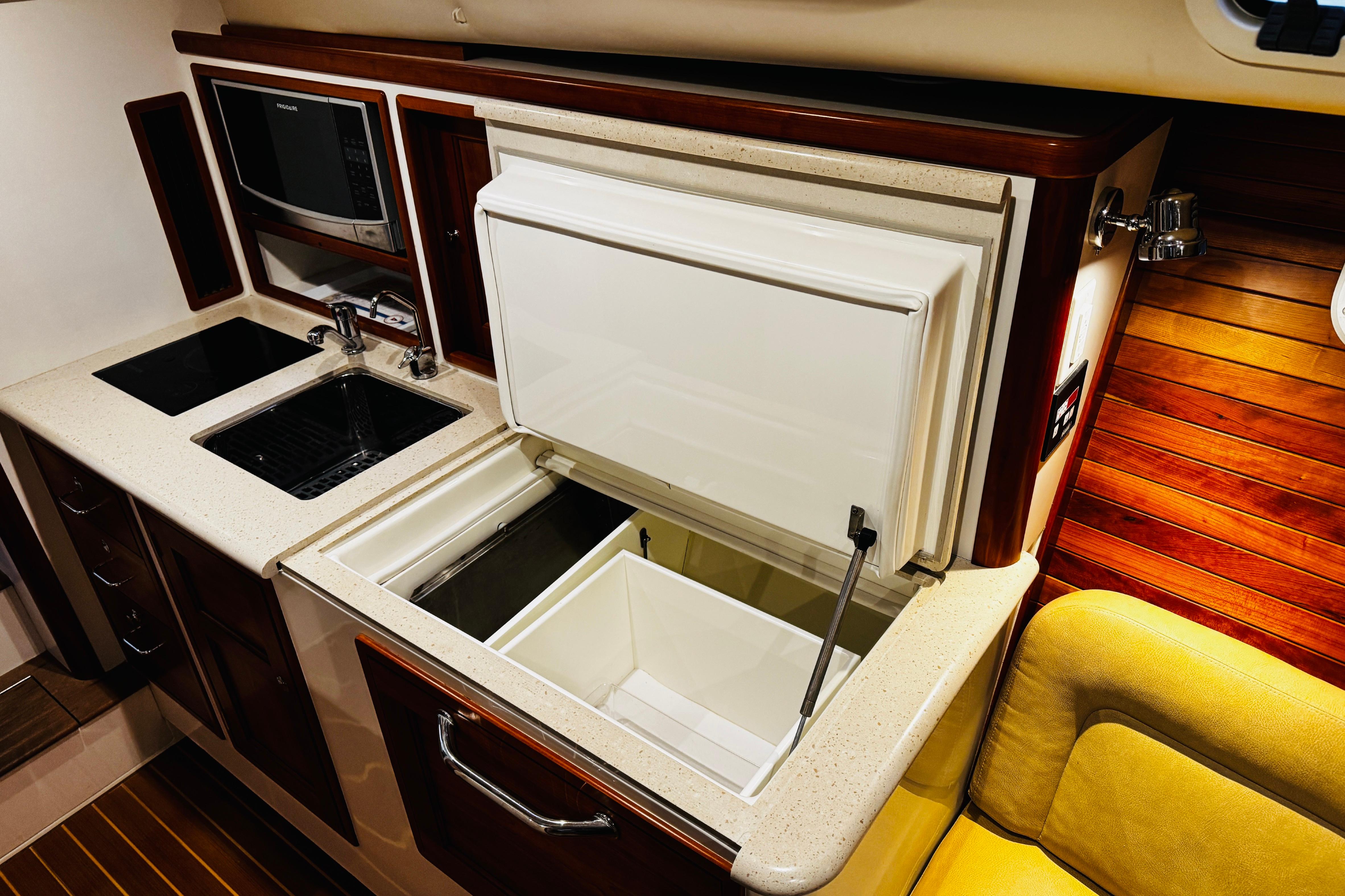 2015 MJM 36z Express yacht galley with sink, microwave, and open refrigerator.