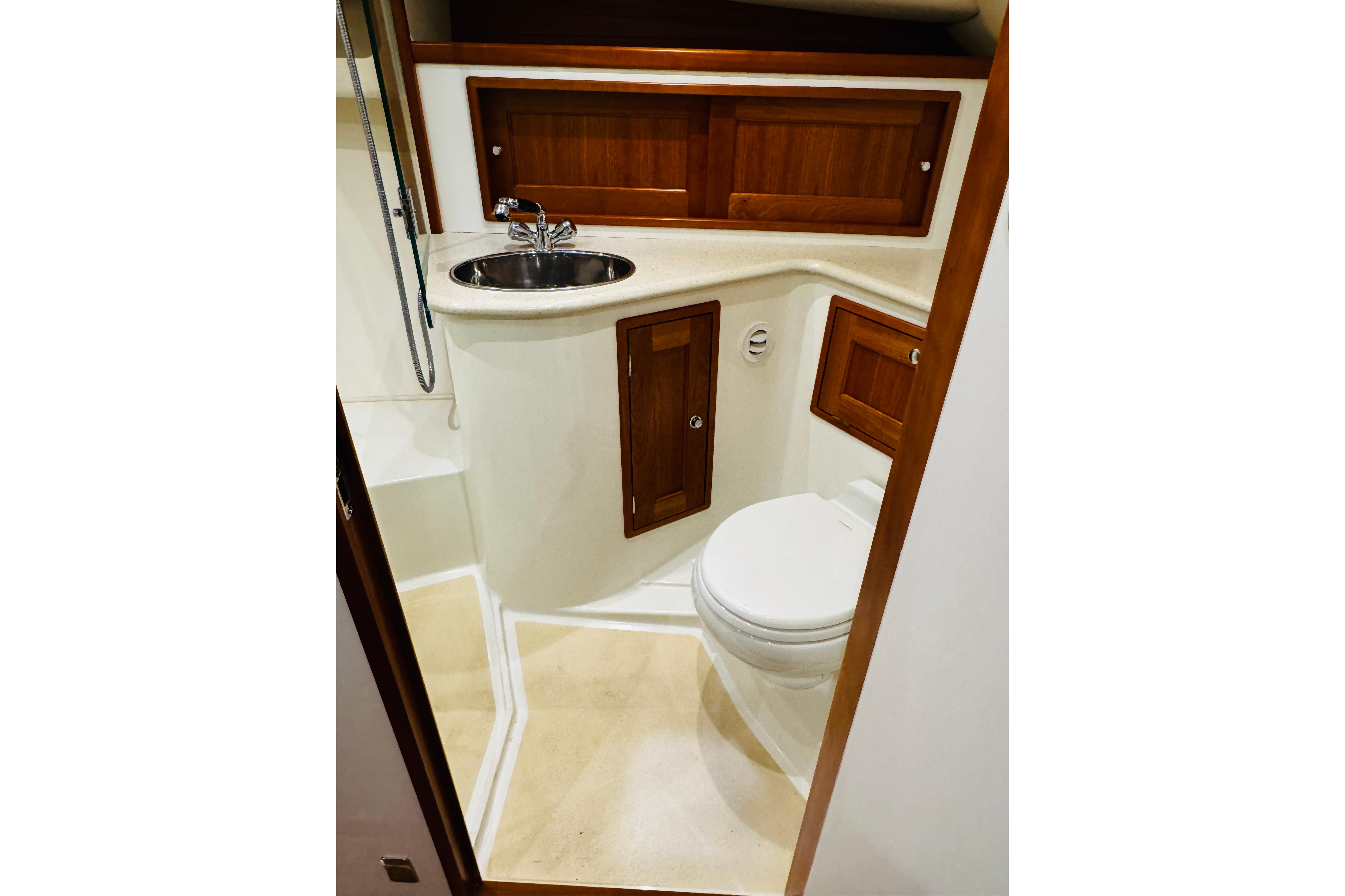 2015 MJM 36z Express yacht bathroom with sink, toilet, and wooden cabinetry.