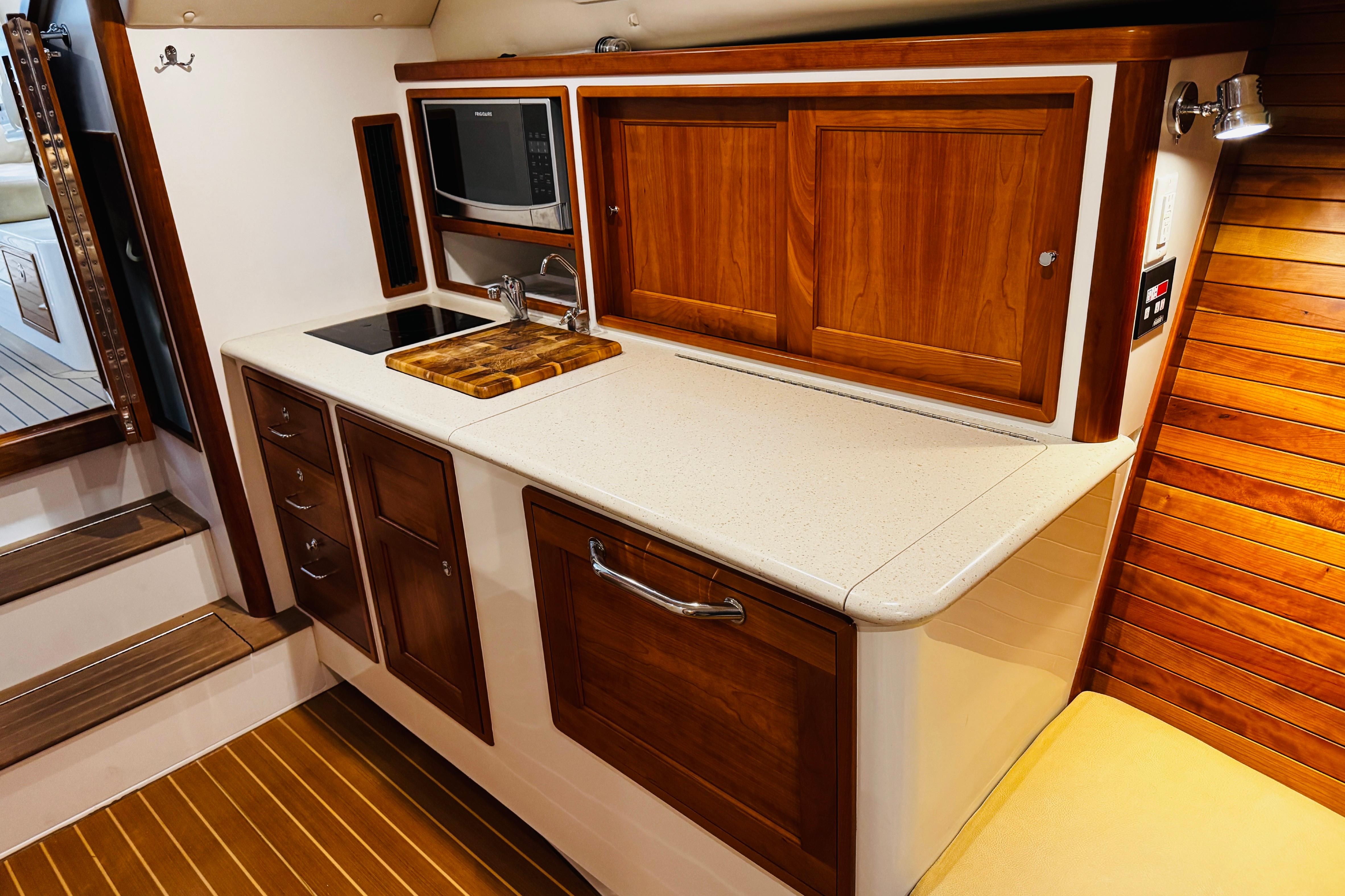 2015 MJM 36z Express yacht interior with wooden cabinetry and modern kitchenette.