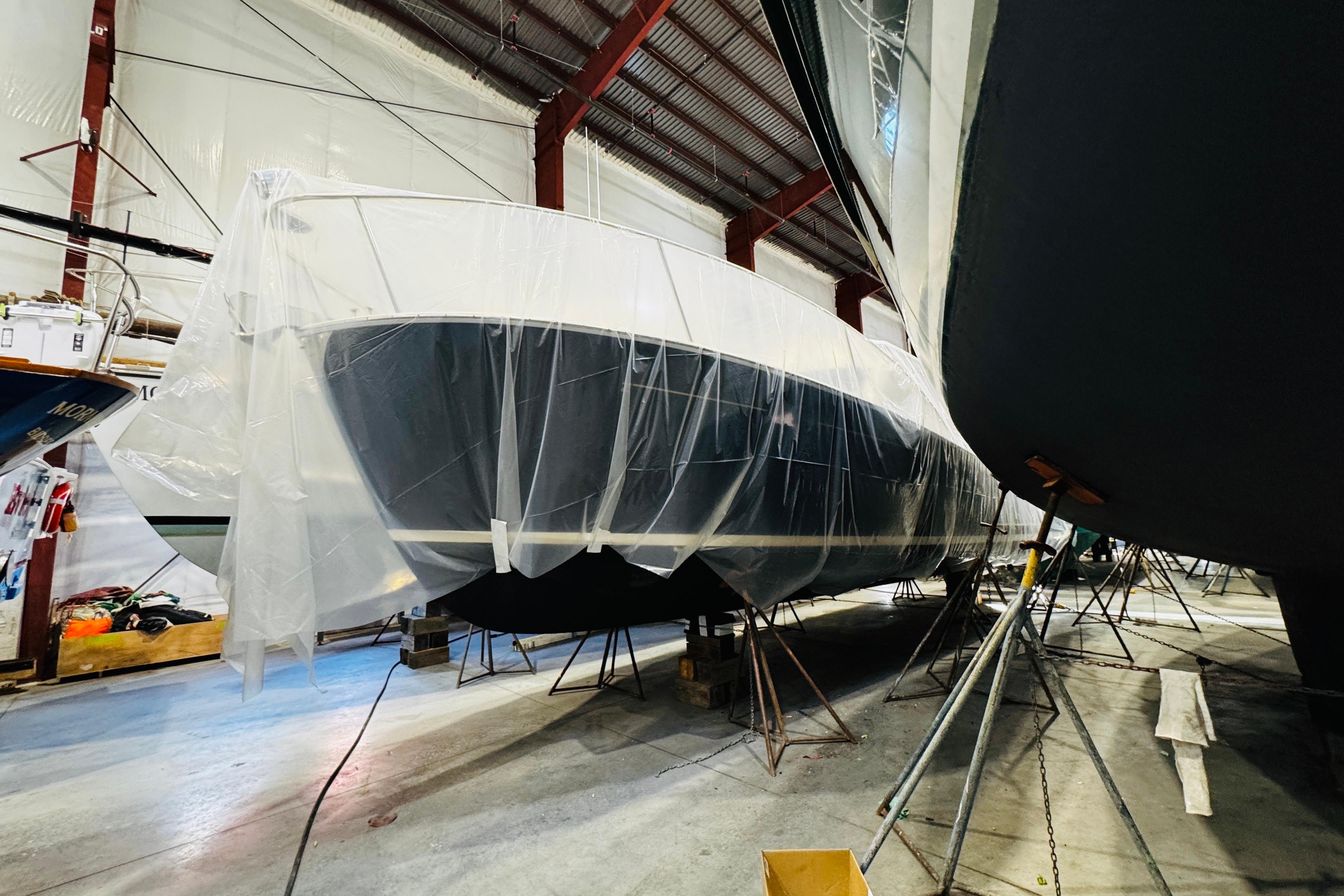 2015 MJM 36z Express yacht covered in plastic, stored indoors.